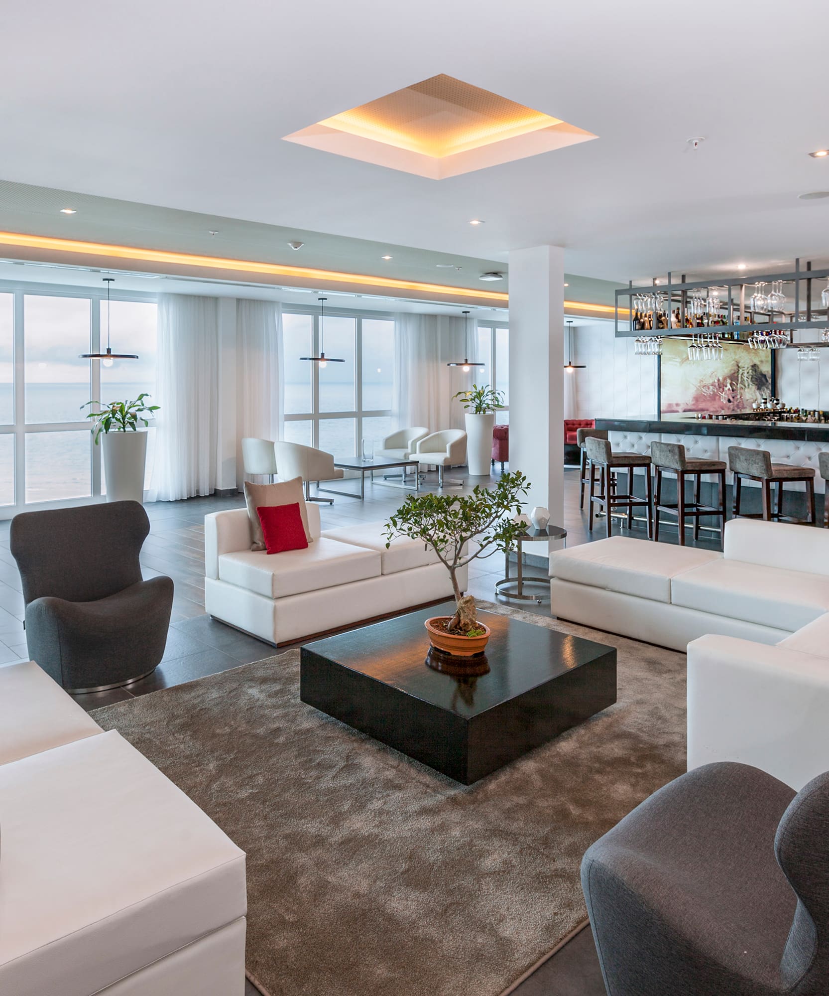 a room with white furniture and a bar