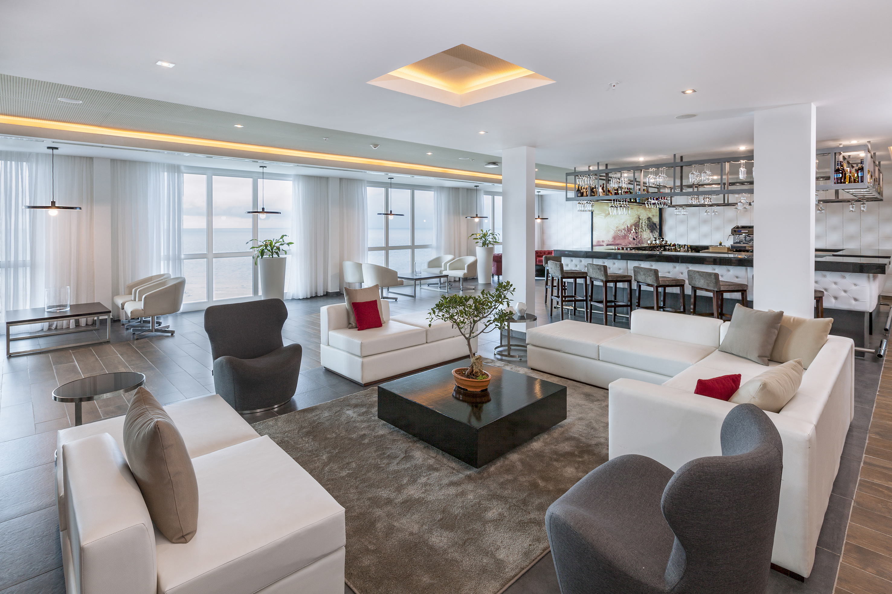 a room with white furniture and a bar