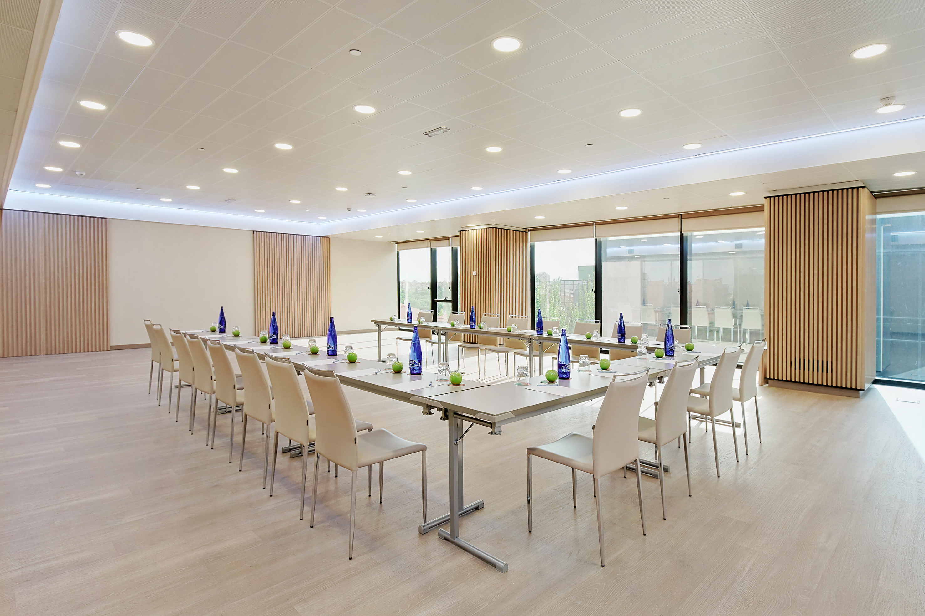 Modern U-shape meeting room setup with natural light and wood paneling.