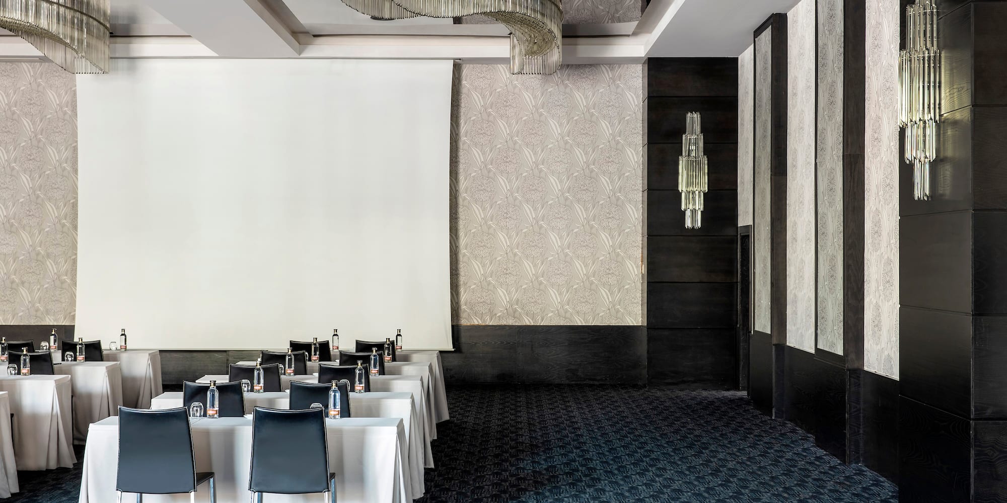 a room with a white screen and tables and chairs