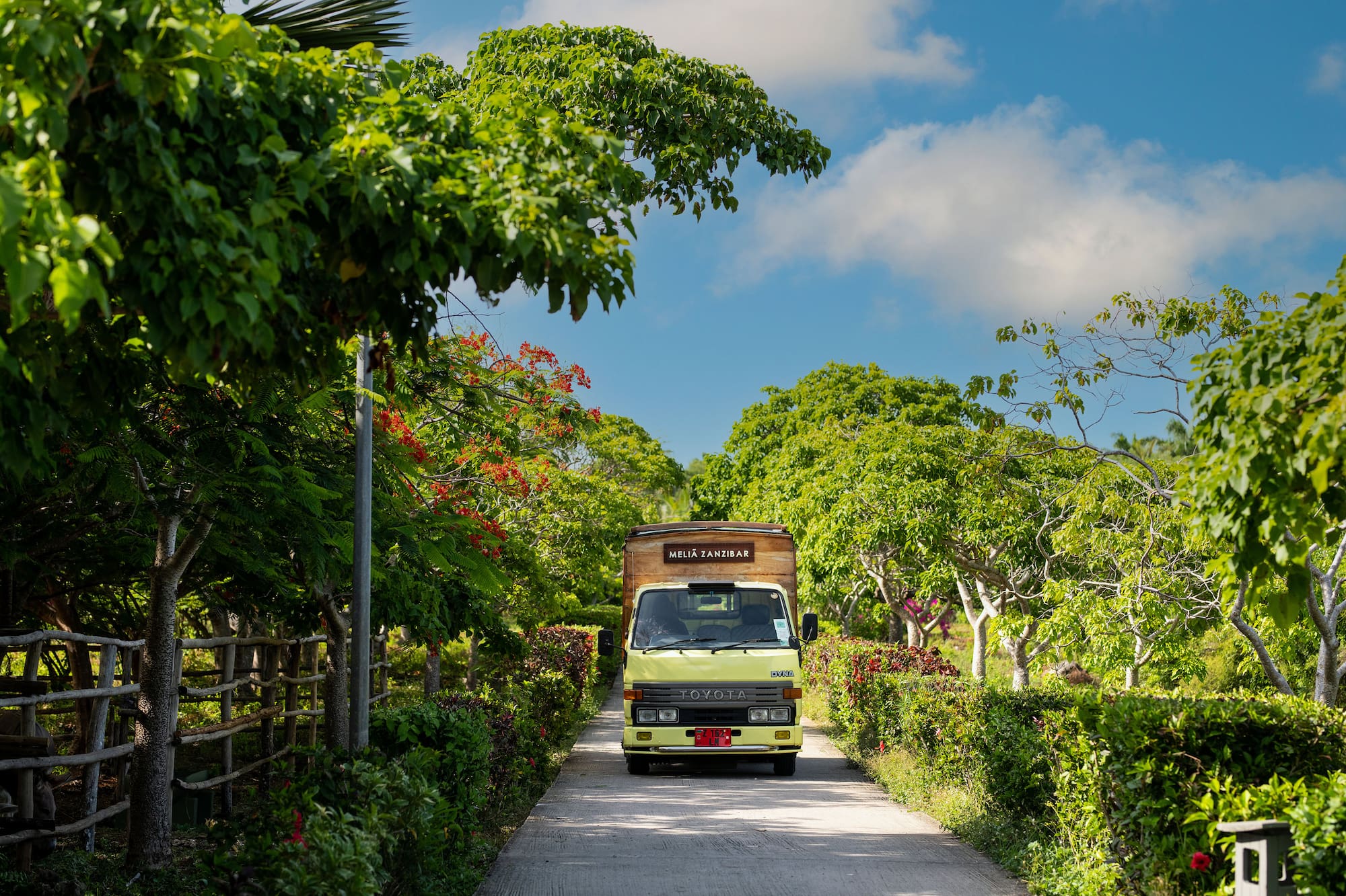 a truck driving down a road with trees and bushes