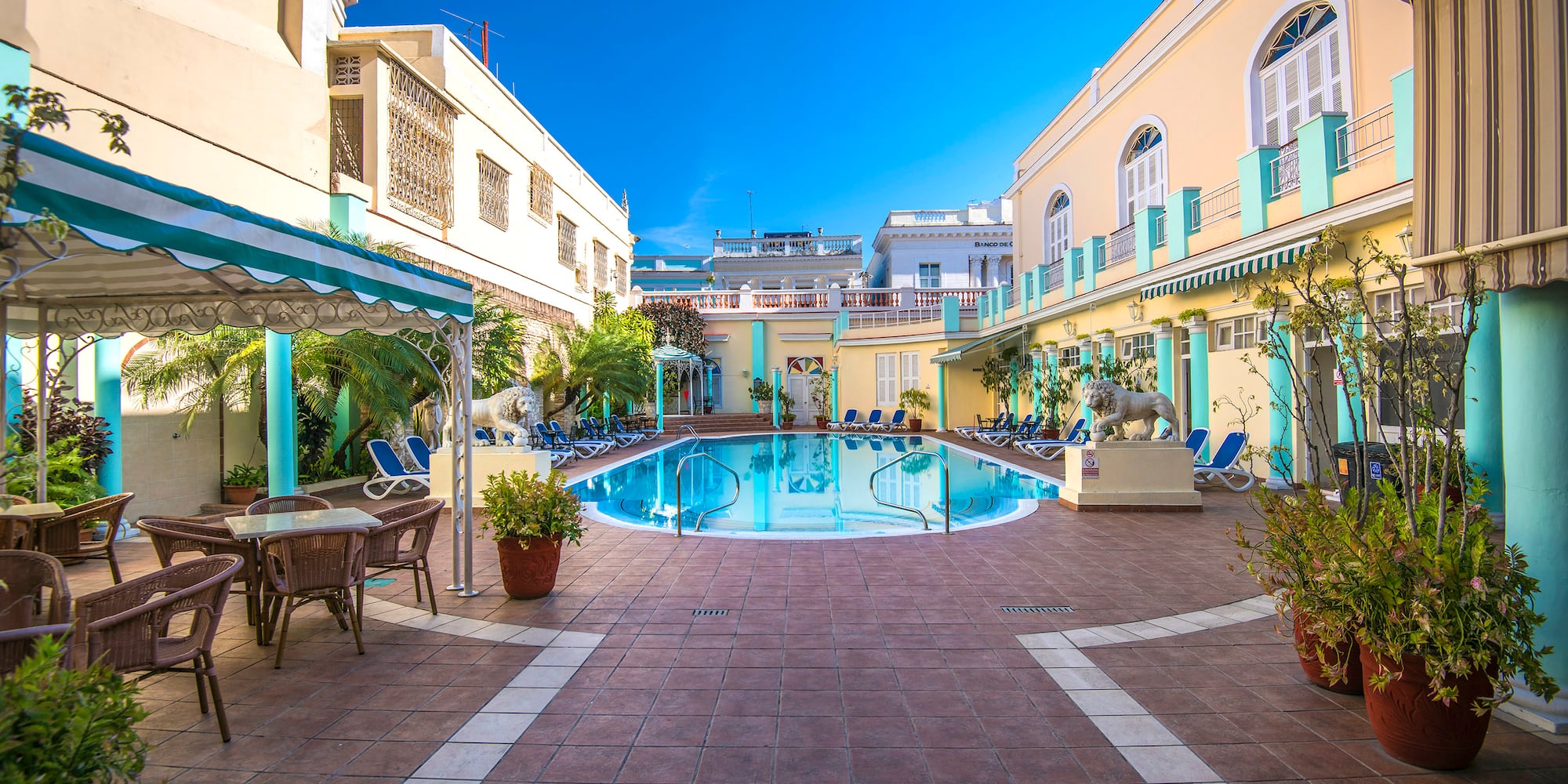 a pool with chairs and tables in front of a building