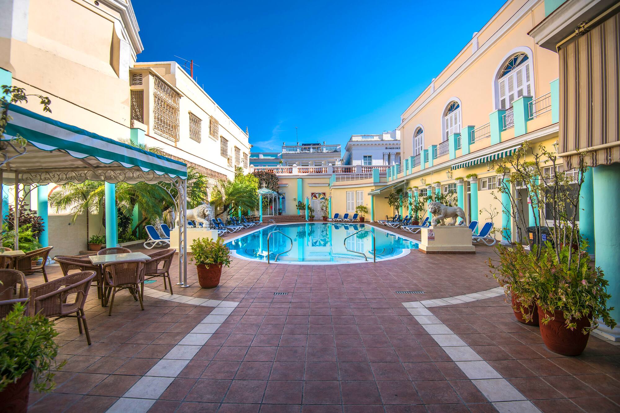 a pool with chairs and tables in front of a building