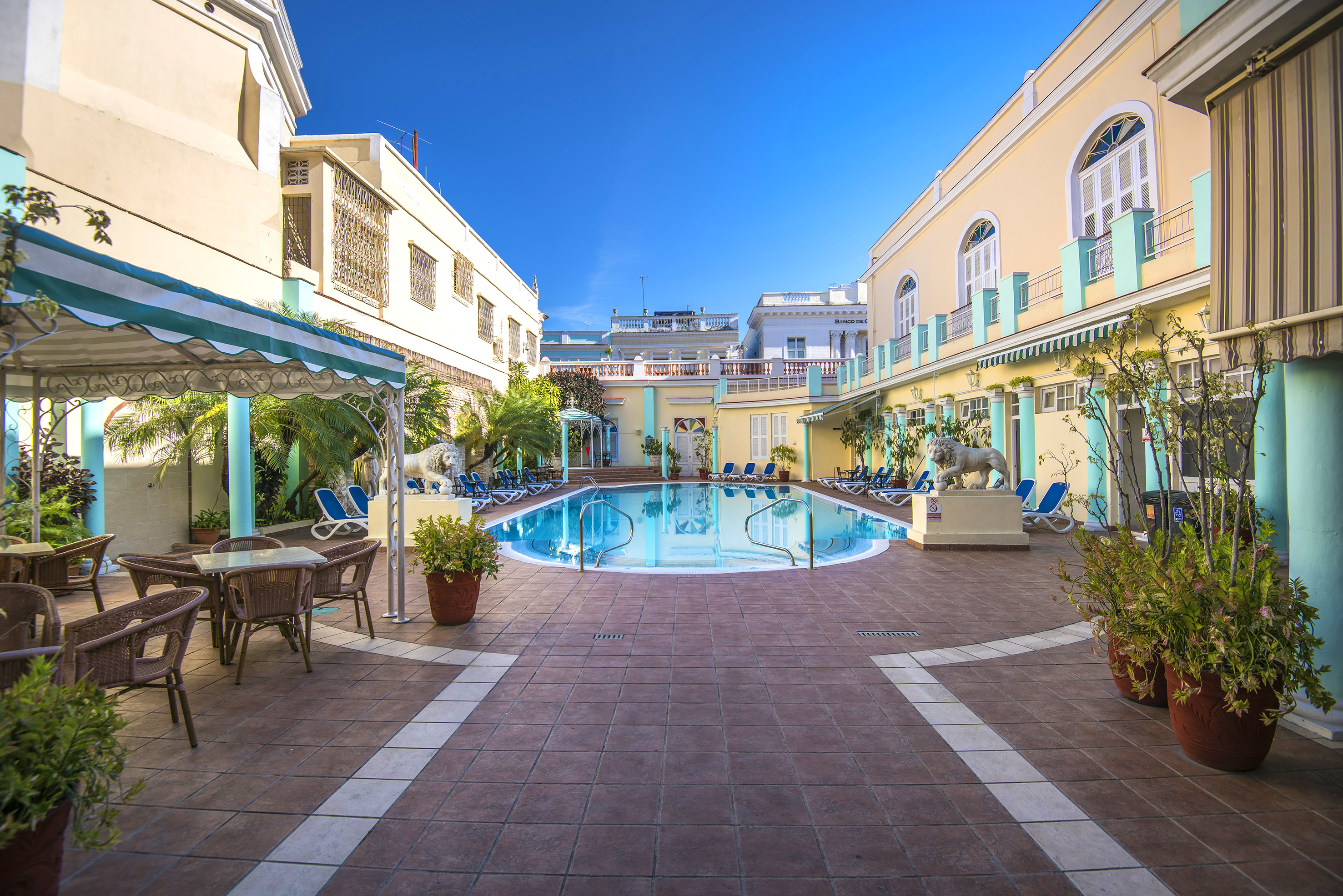 a pool with chairs and tables in front of a building