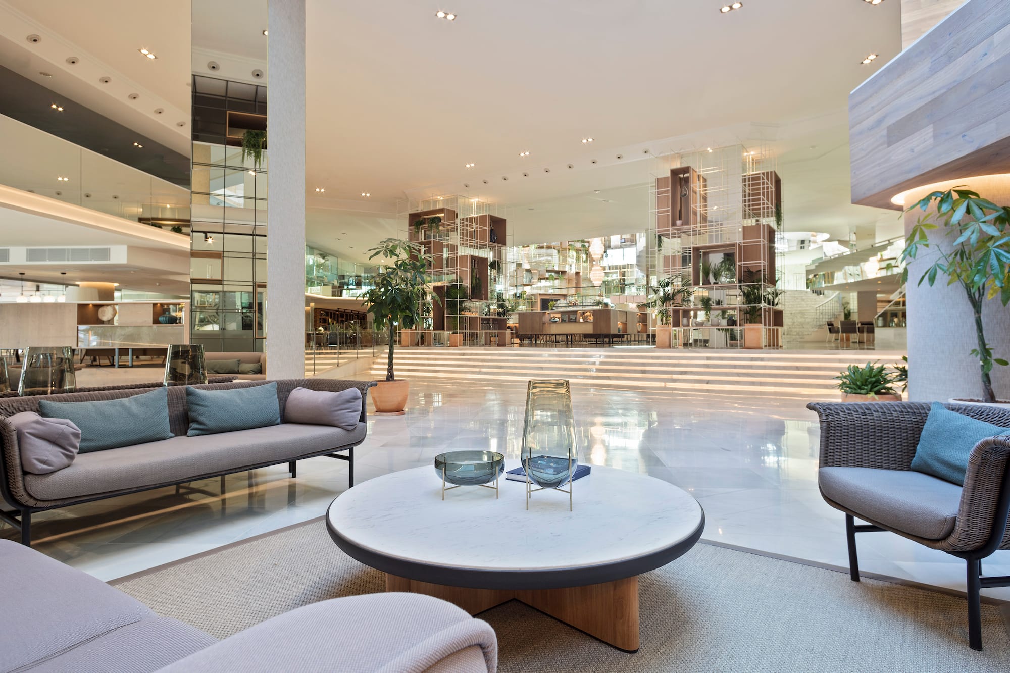 Modern hotel lobby lounge with contemporary seating, white marble floor, and plants.