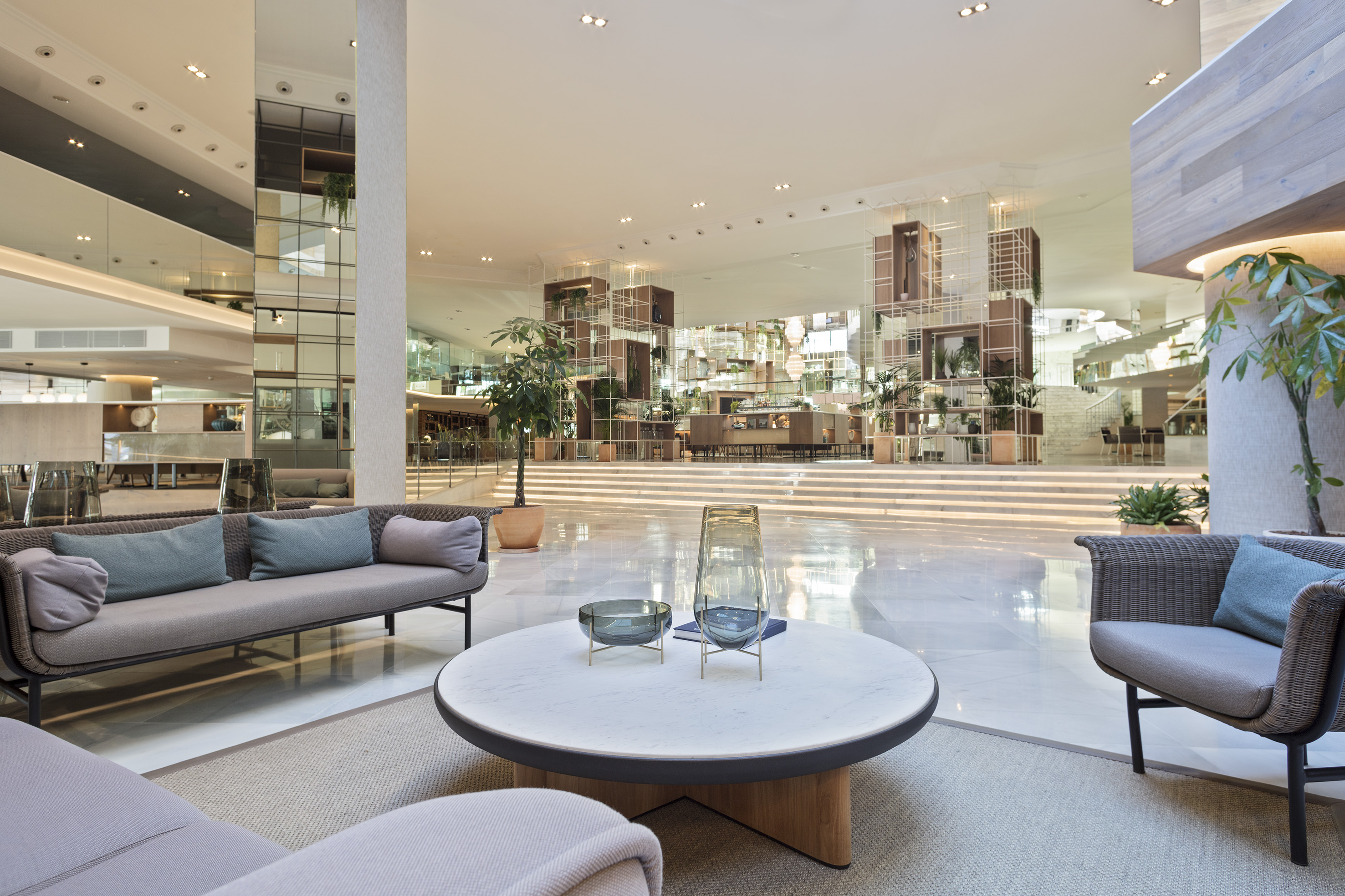 Modern hotel lobby lounge with contemporary seating, white marble floor, and plants.