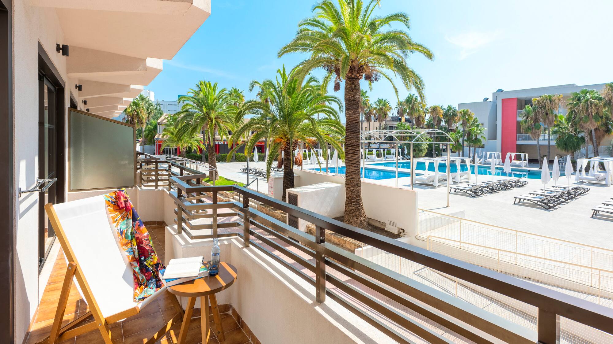 a balcony with palm trees and a pool