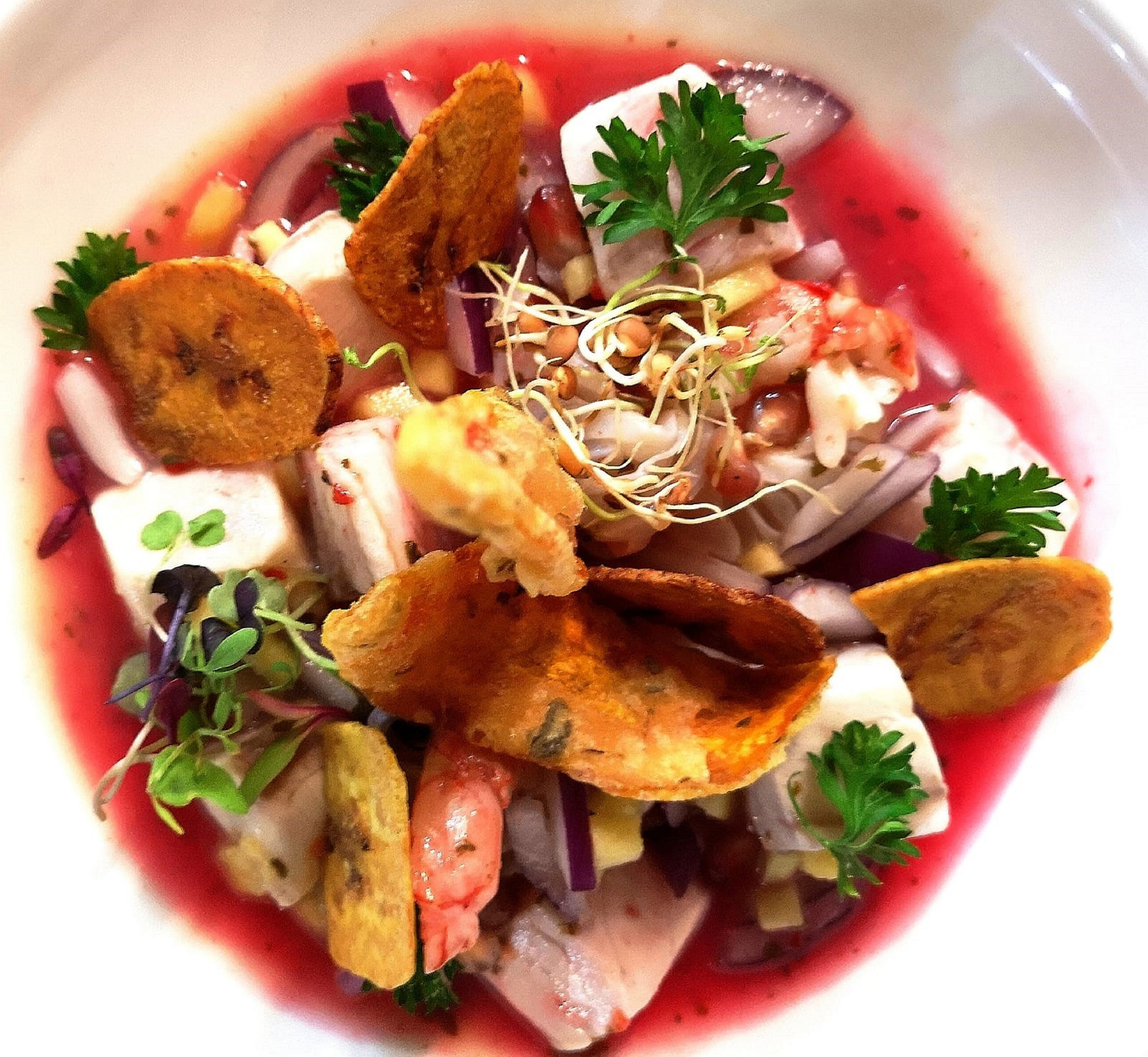 Fresh ceviche with fish, shrimp, plantain chips, red onion, and microgreens.