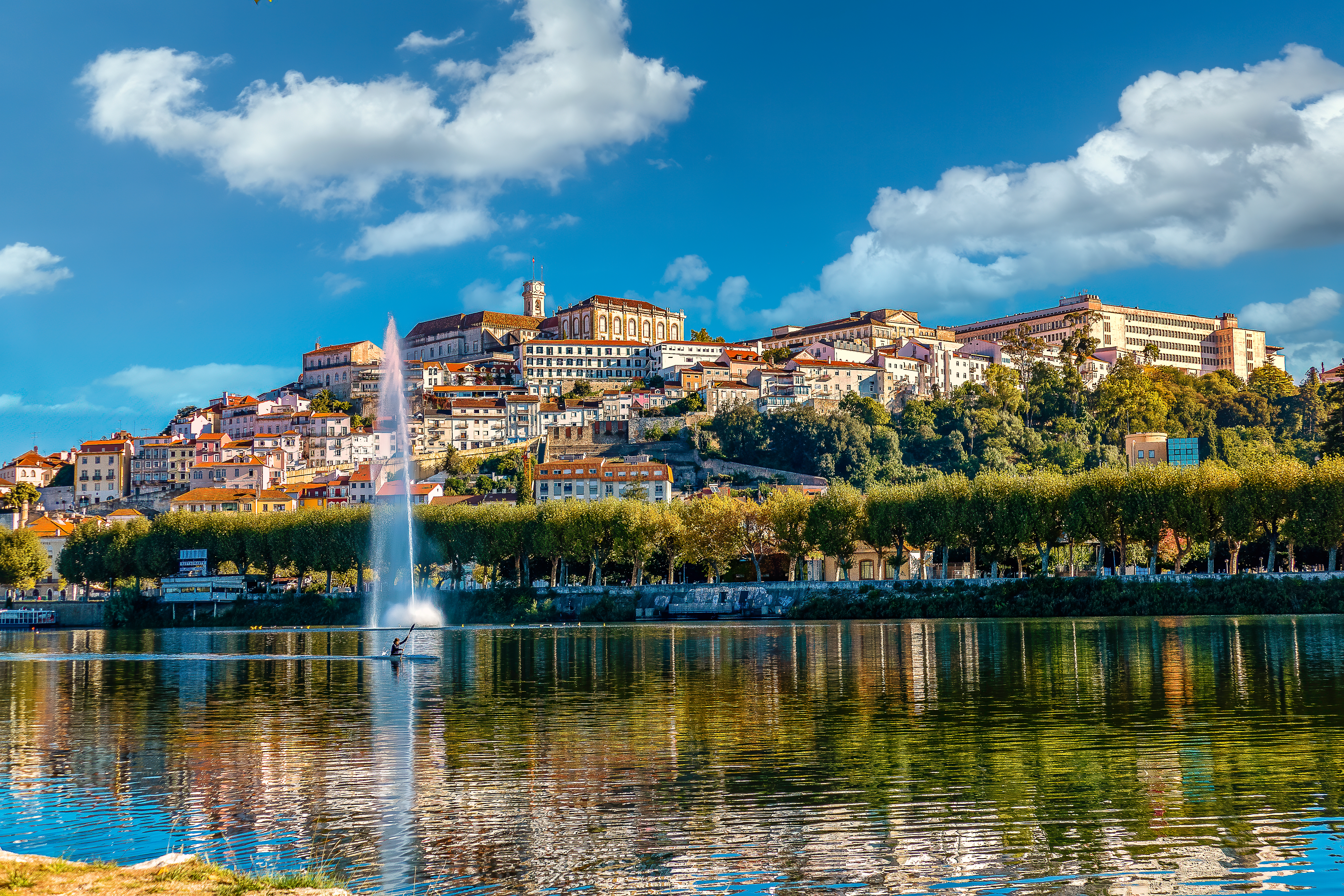 Historic Coimbra cityscape, university on hill, Mondego River, fountain.