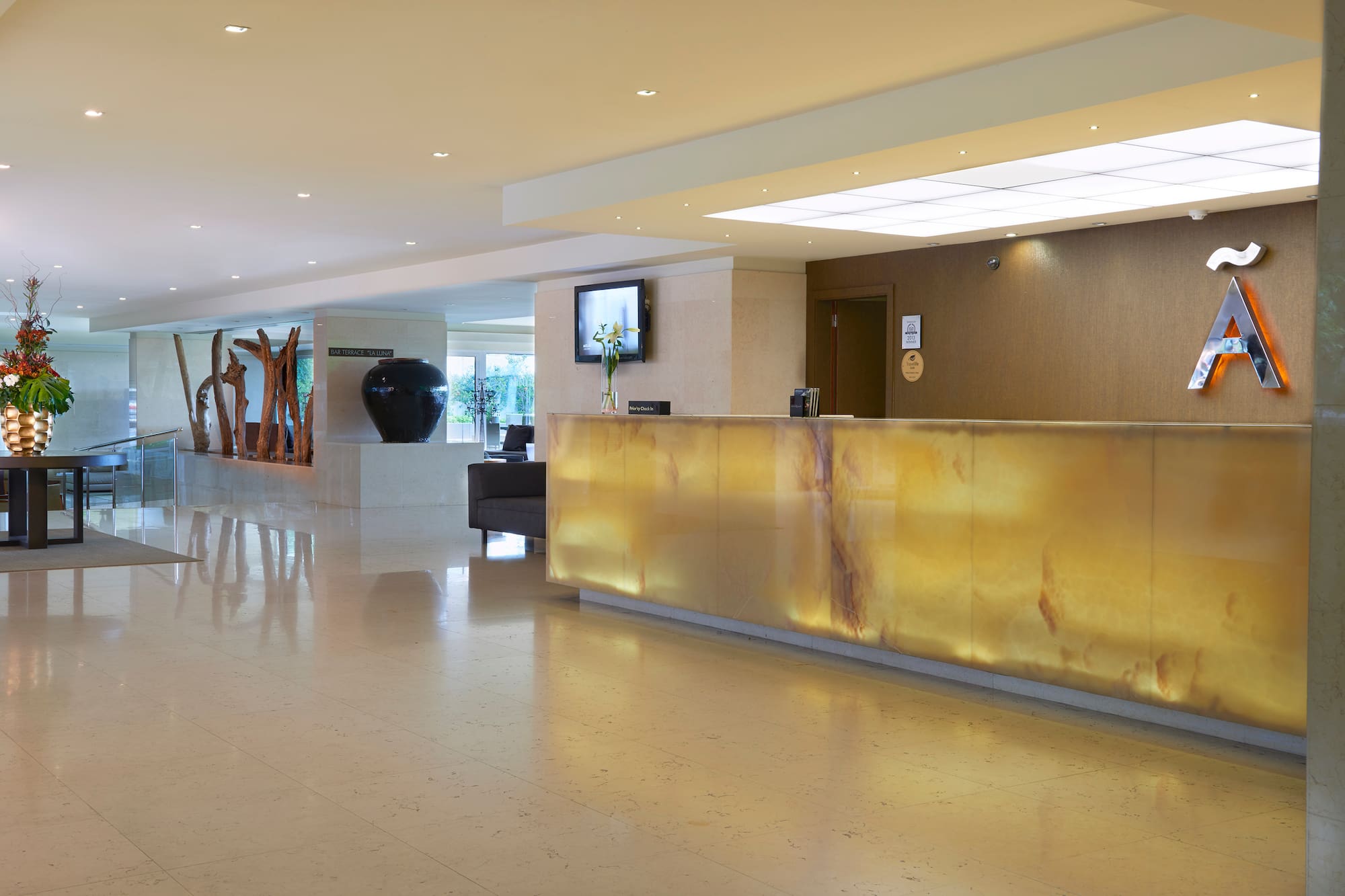 Glowing onyx reception desk in a modern hotel lobby with polished marble floor.