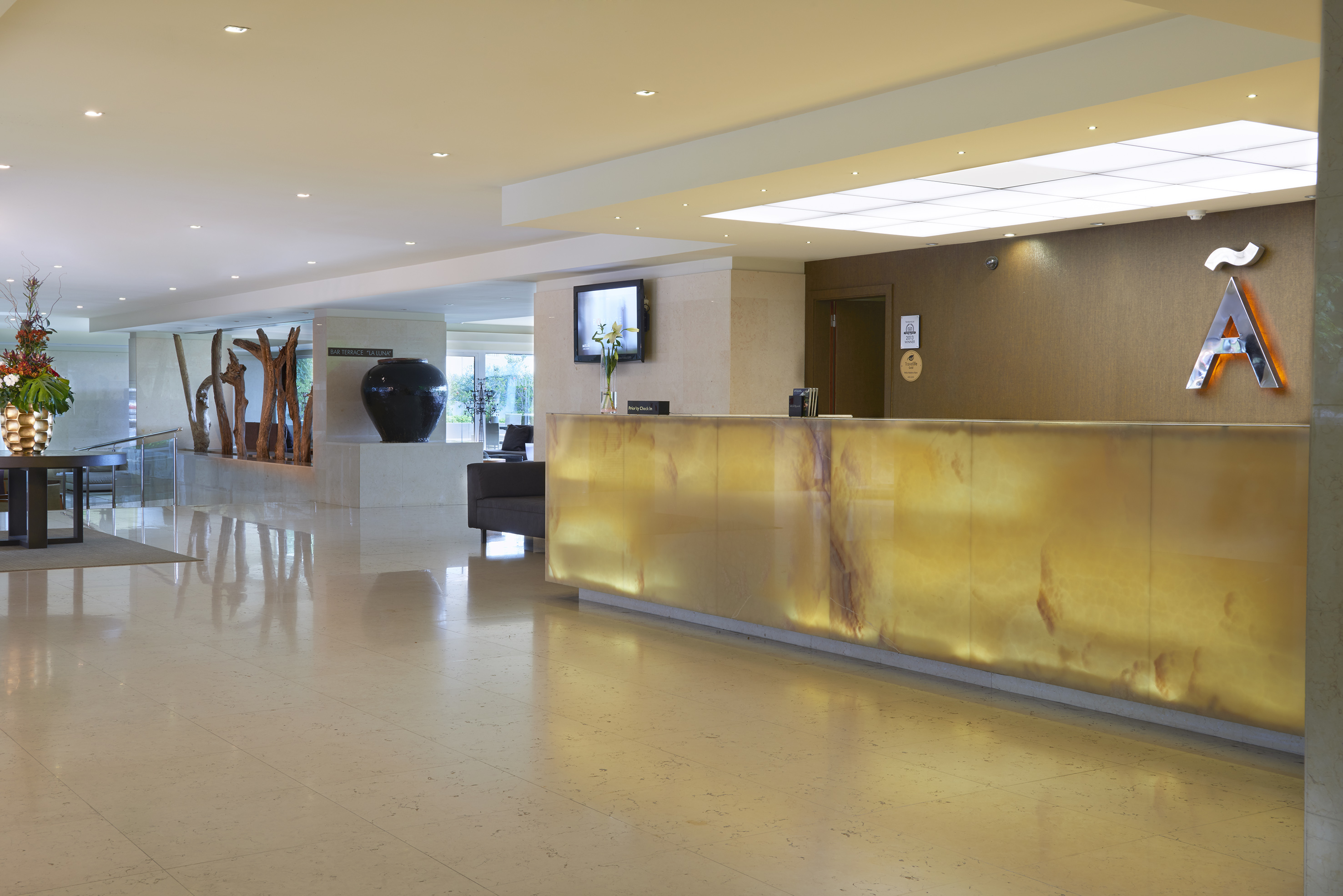 Glowing onyx reception desk in a modern hotel lobby with polished marble floor.