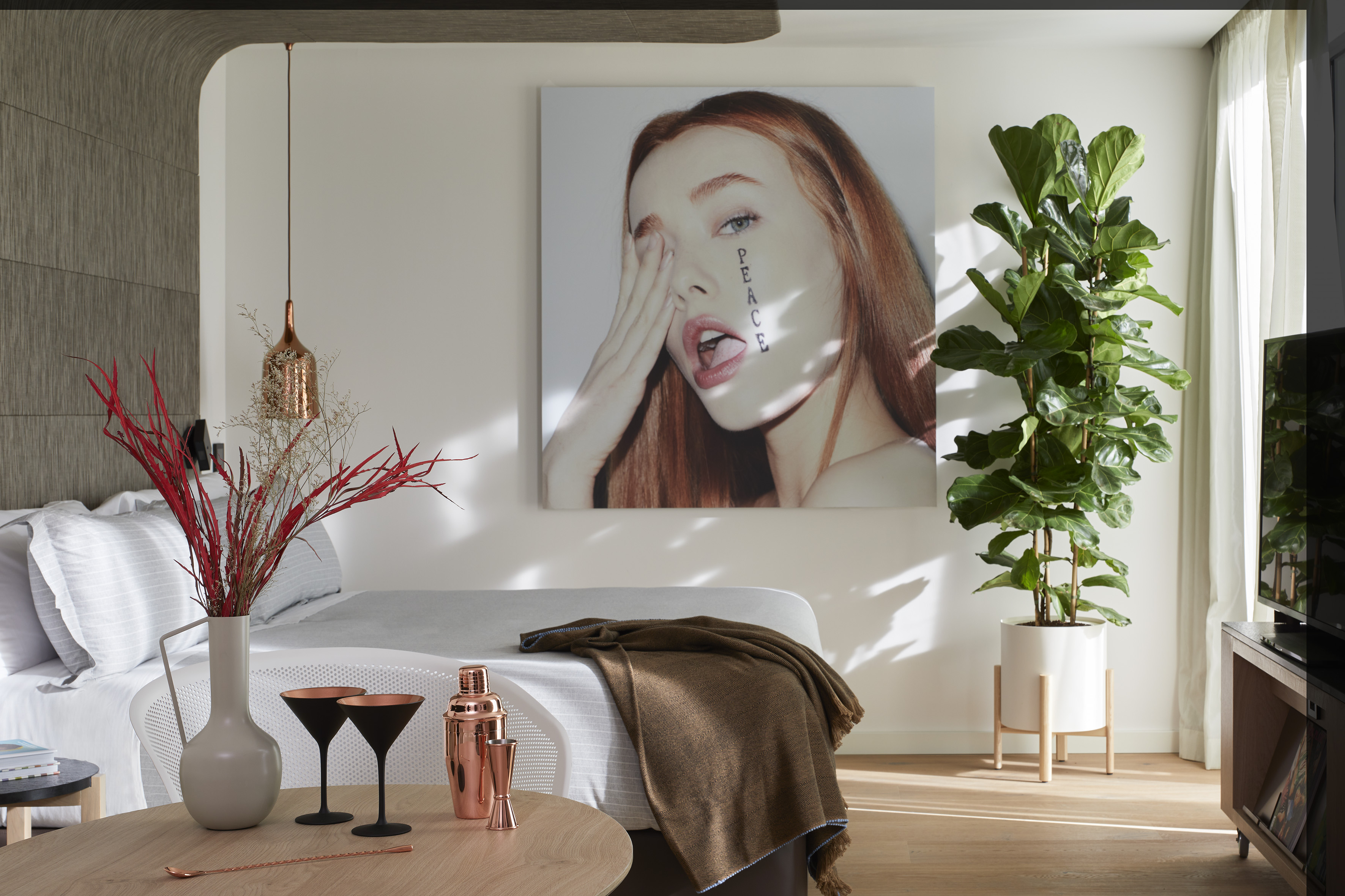 Modern bedroom with large portrait art, fiddle-leaf fig plant, and cocktail set.