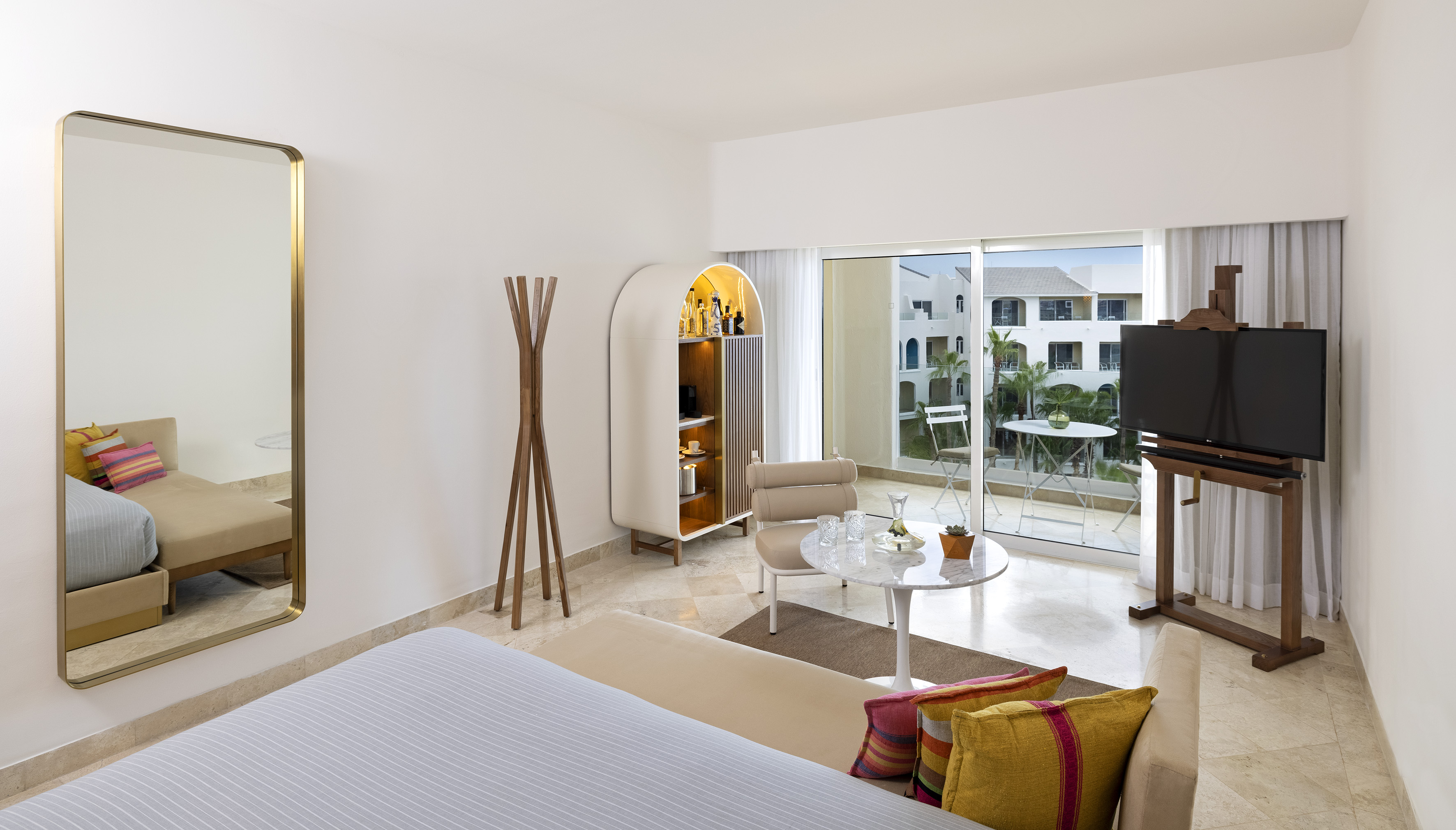 Modern hotel suite with balcony, contemporary decor, bed, and resort view.