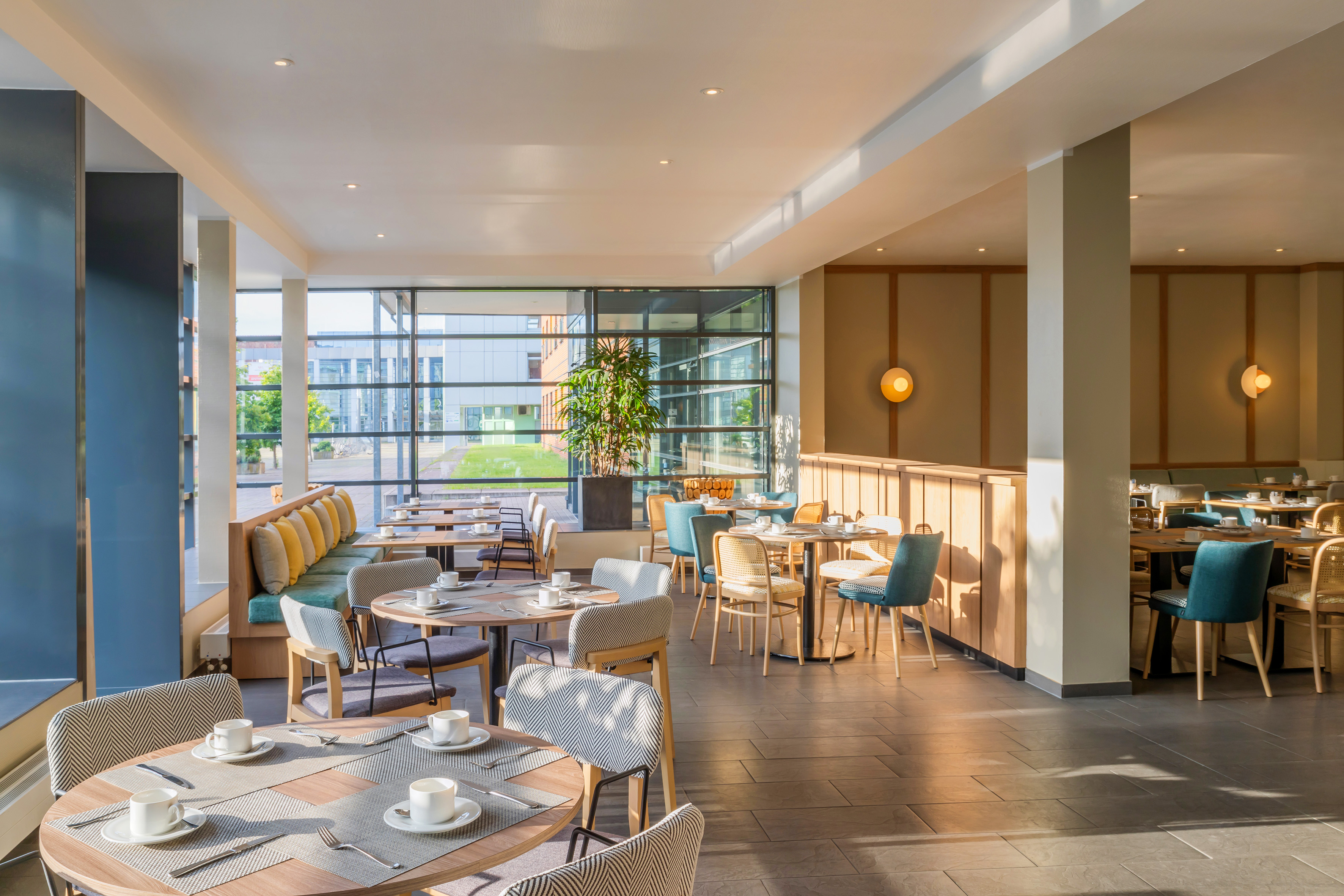 Bright modern restaurant with set tables, varied seating, and large windows.