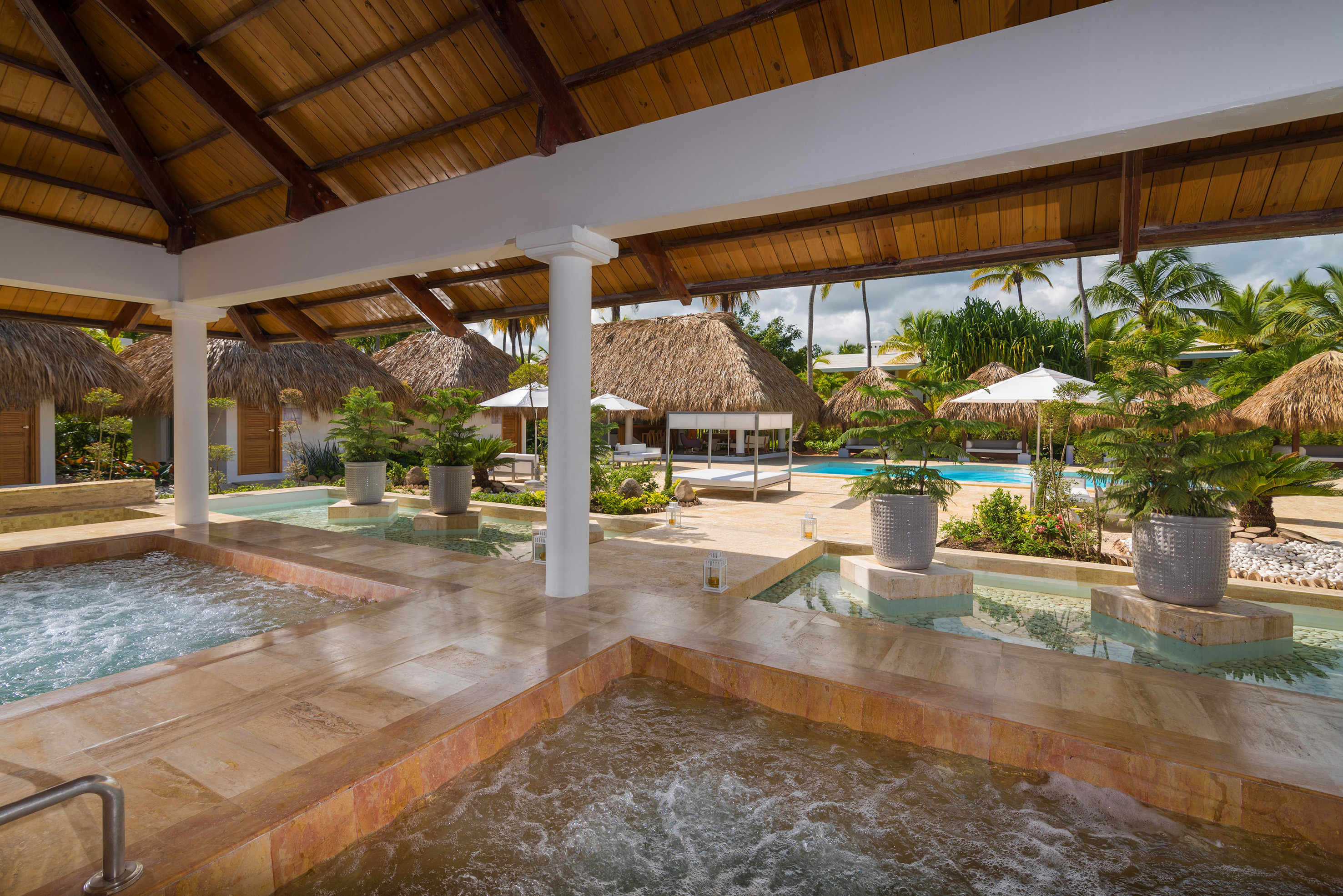 Tropical resort spa featuring hot tubs, pool, and thatched bungalows.