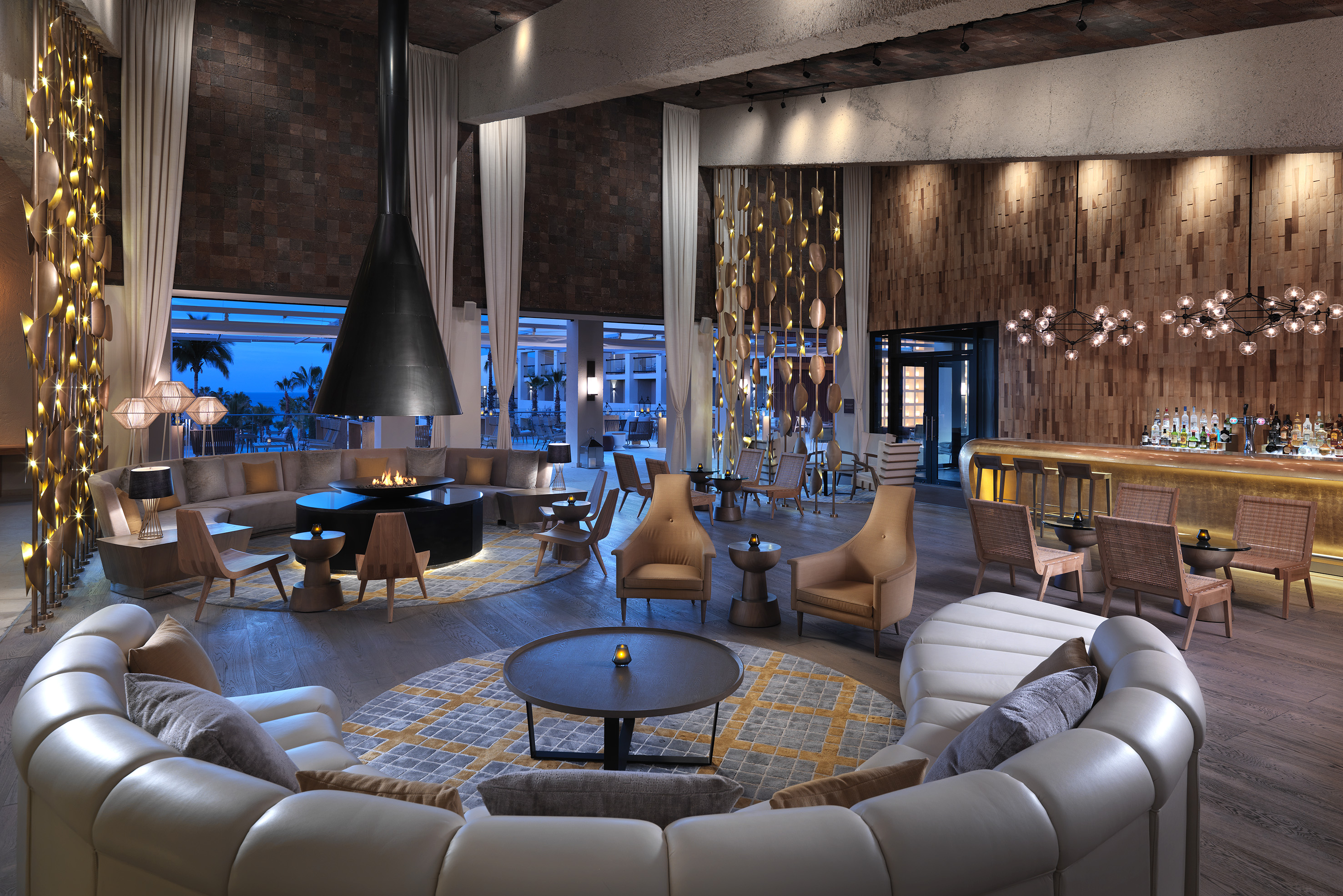 Luxury hotel lobby with circular seating, modern fireplace, and illuminated bar.