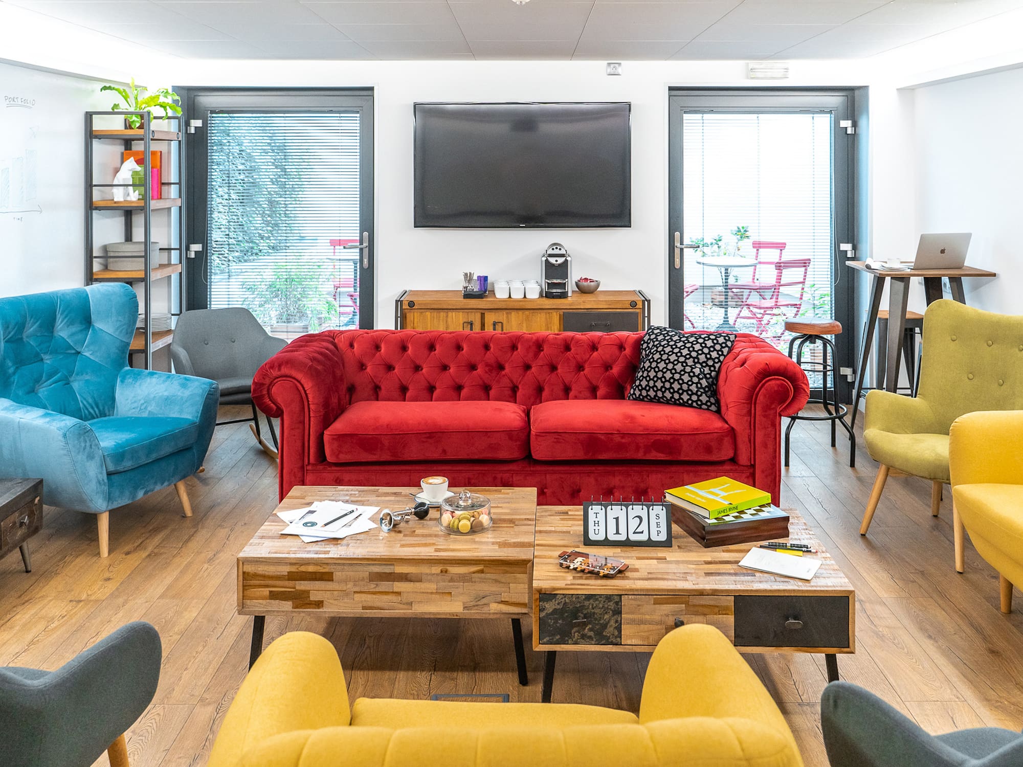 a room with a red couch and blue chairs.