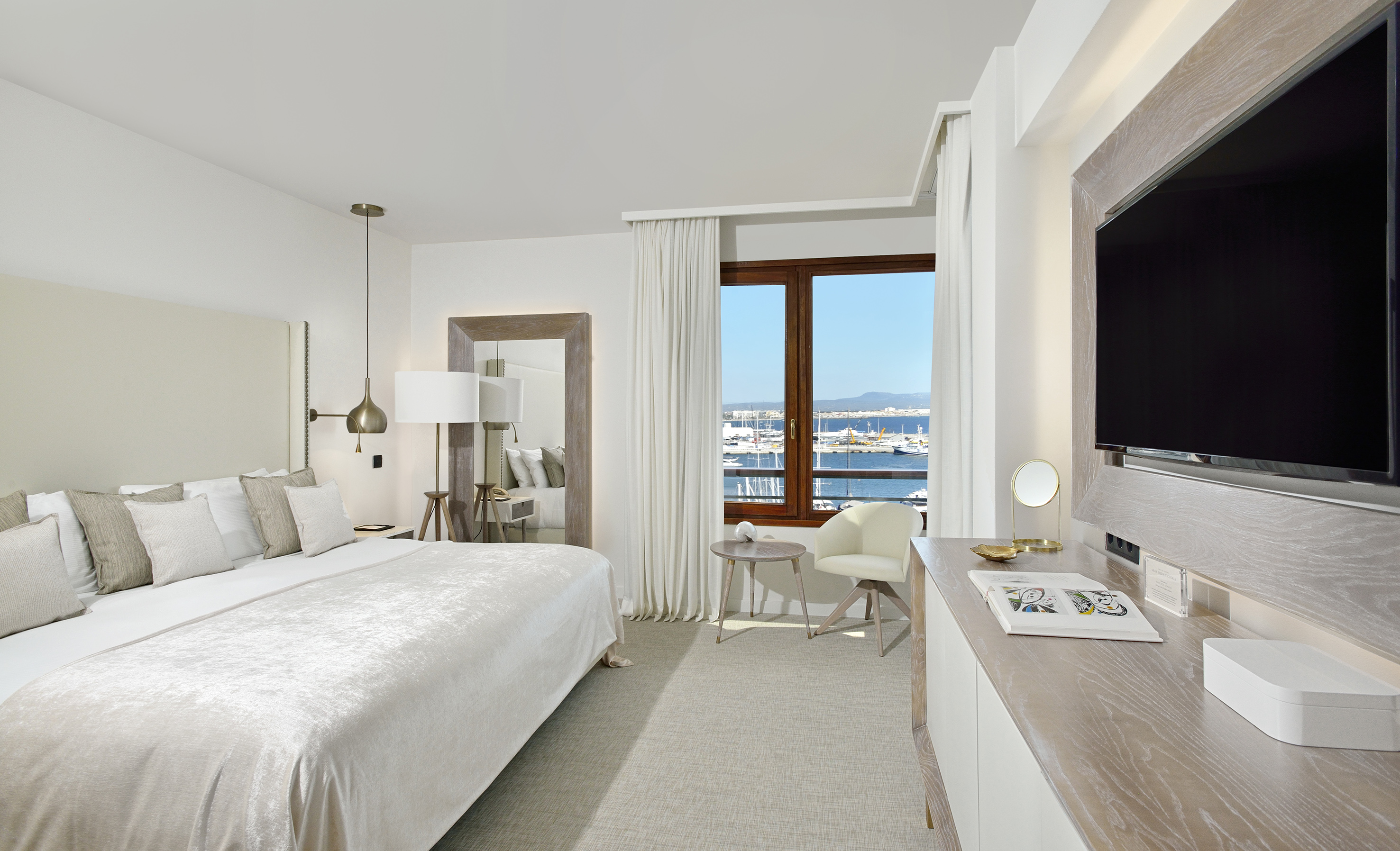 Luxury hotel bedroom with marina view, large bed, and modern decor.