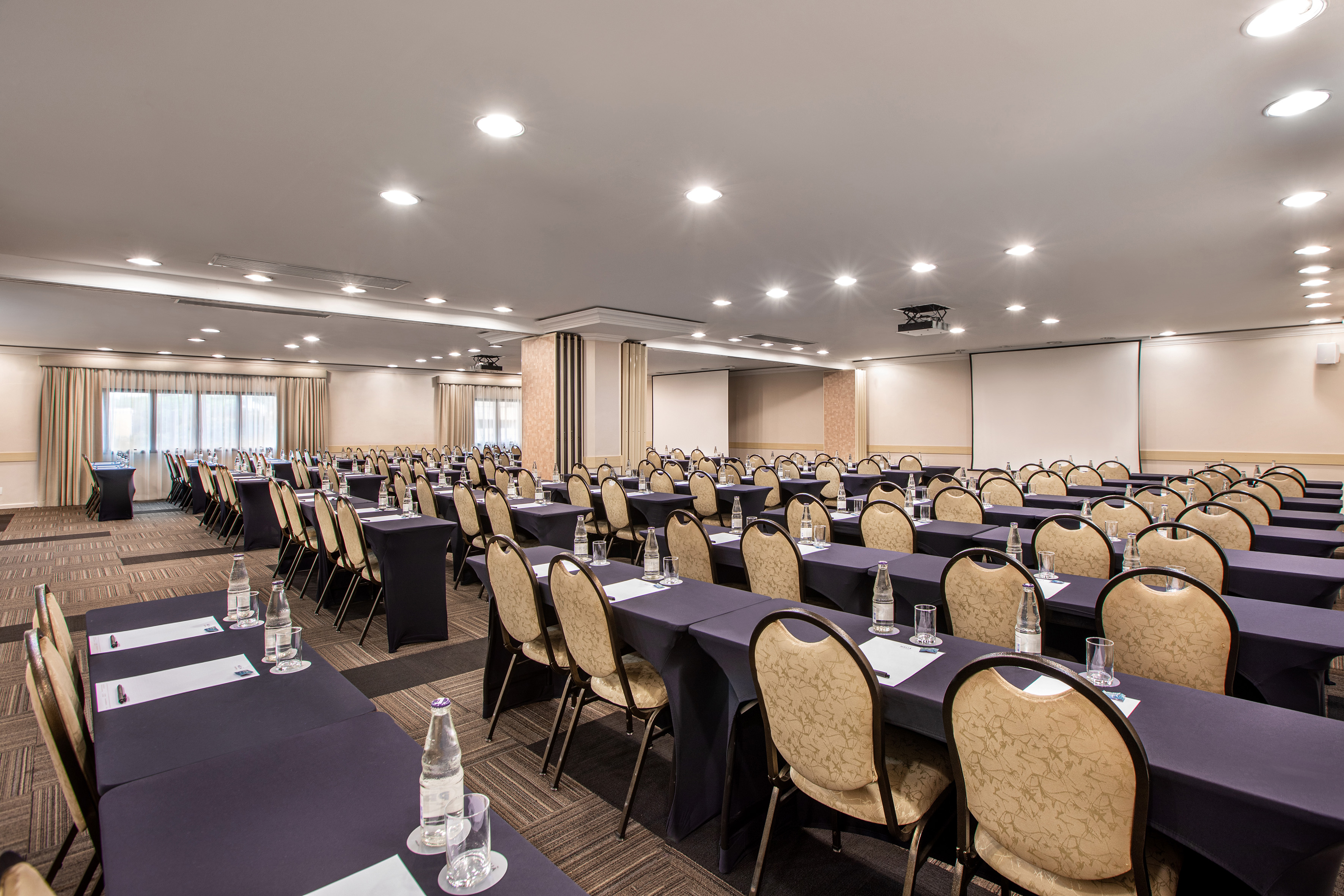 Spacious conference room, classroom setup, dark tables, light chairs, projector.