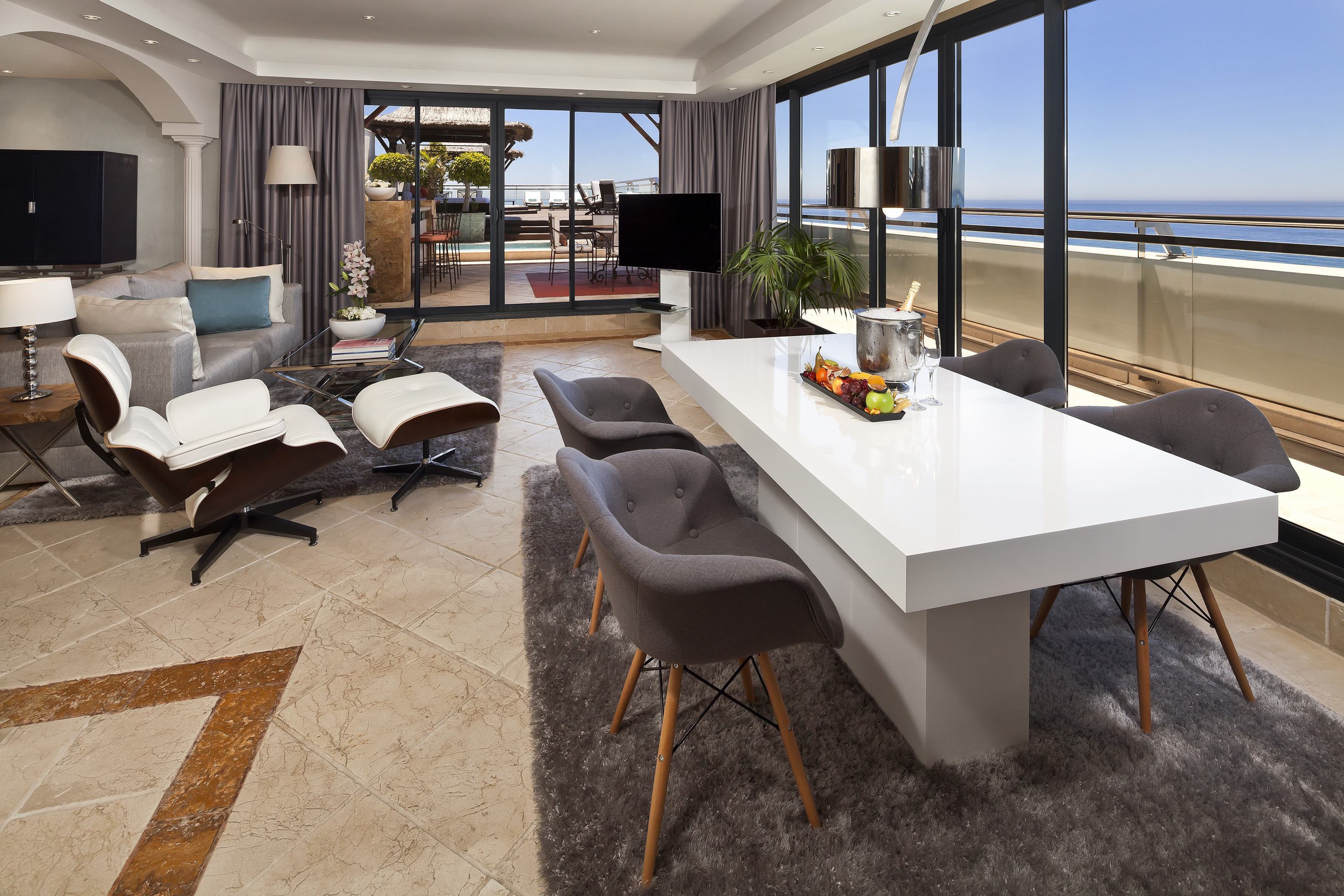 Luxury apartment living room, dining area, and ocean view balcony.