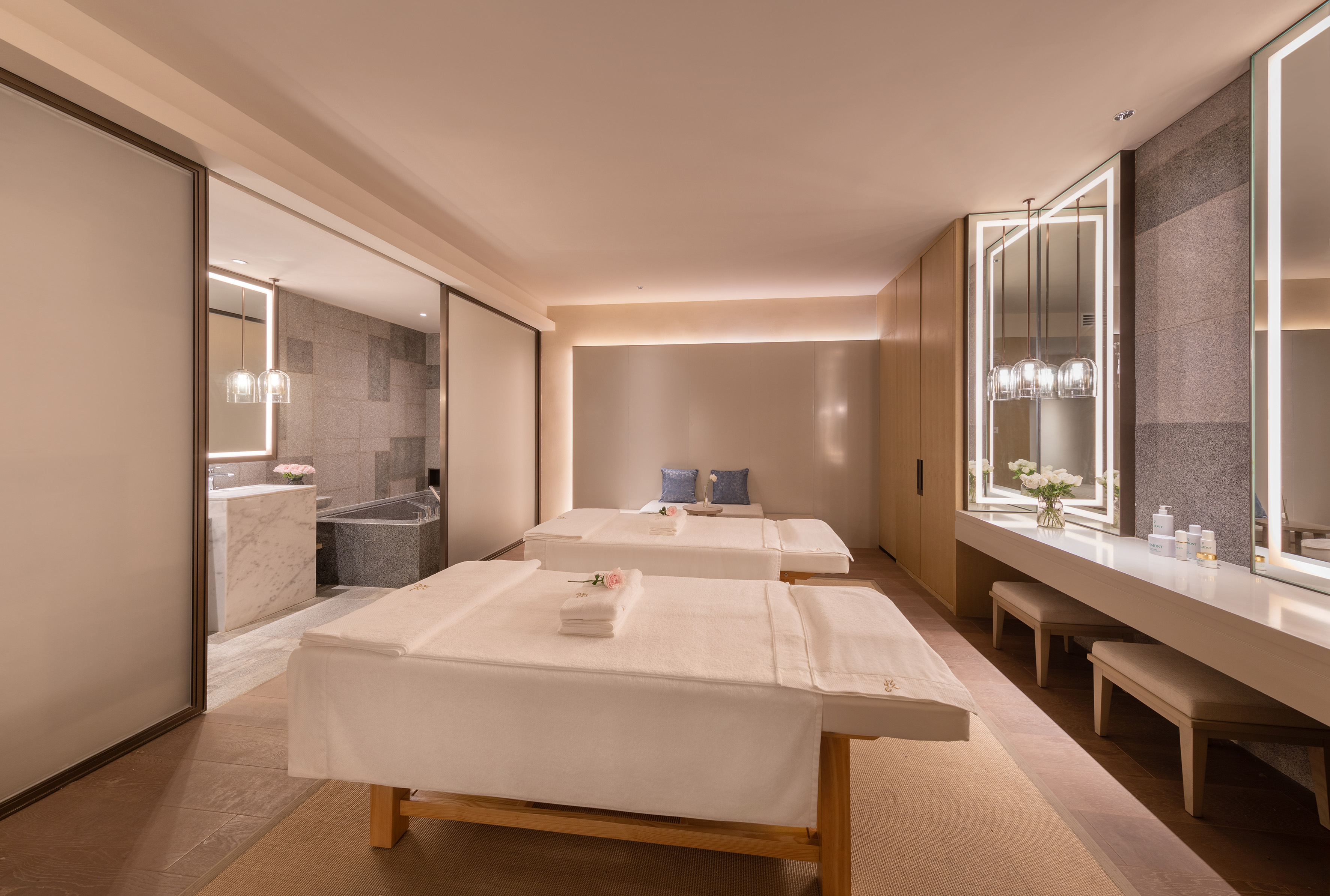 Luxury spa treatment room with two massage beds and vanity area.