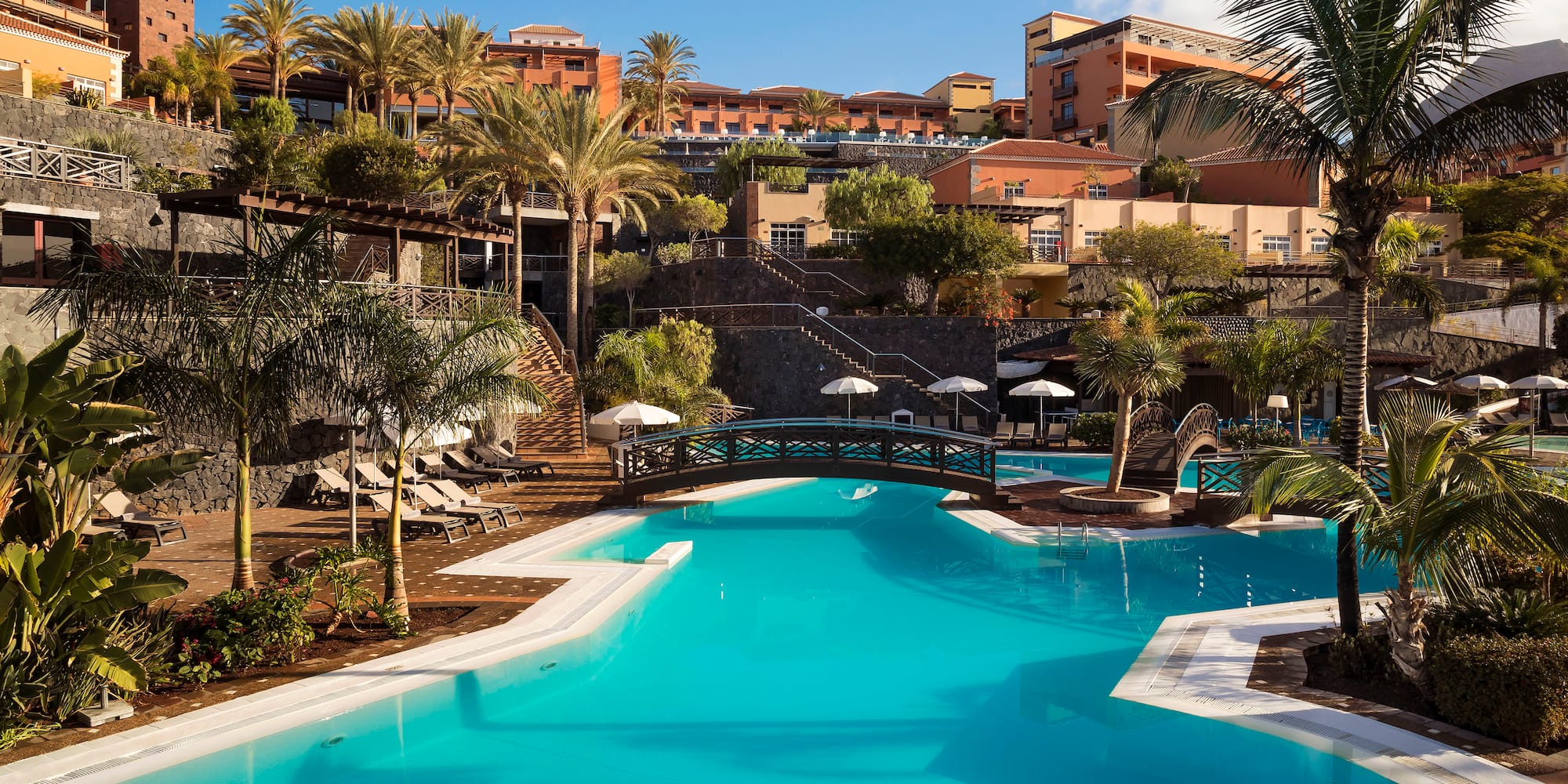 a swimming pool with palm trees and buildings in the background