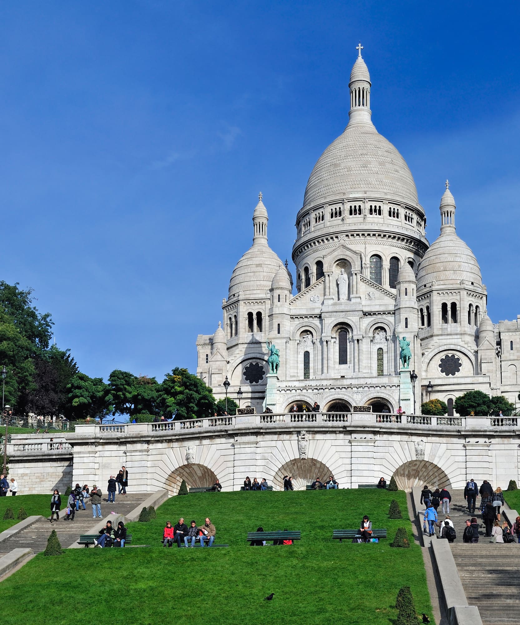 a large white building with a dome and a steeple and people walking on the grass with Sacré-Cœur, Paris in the background