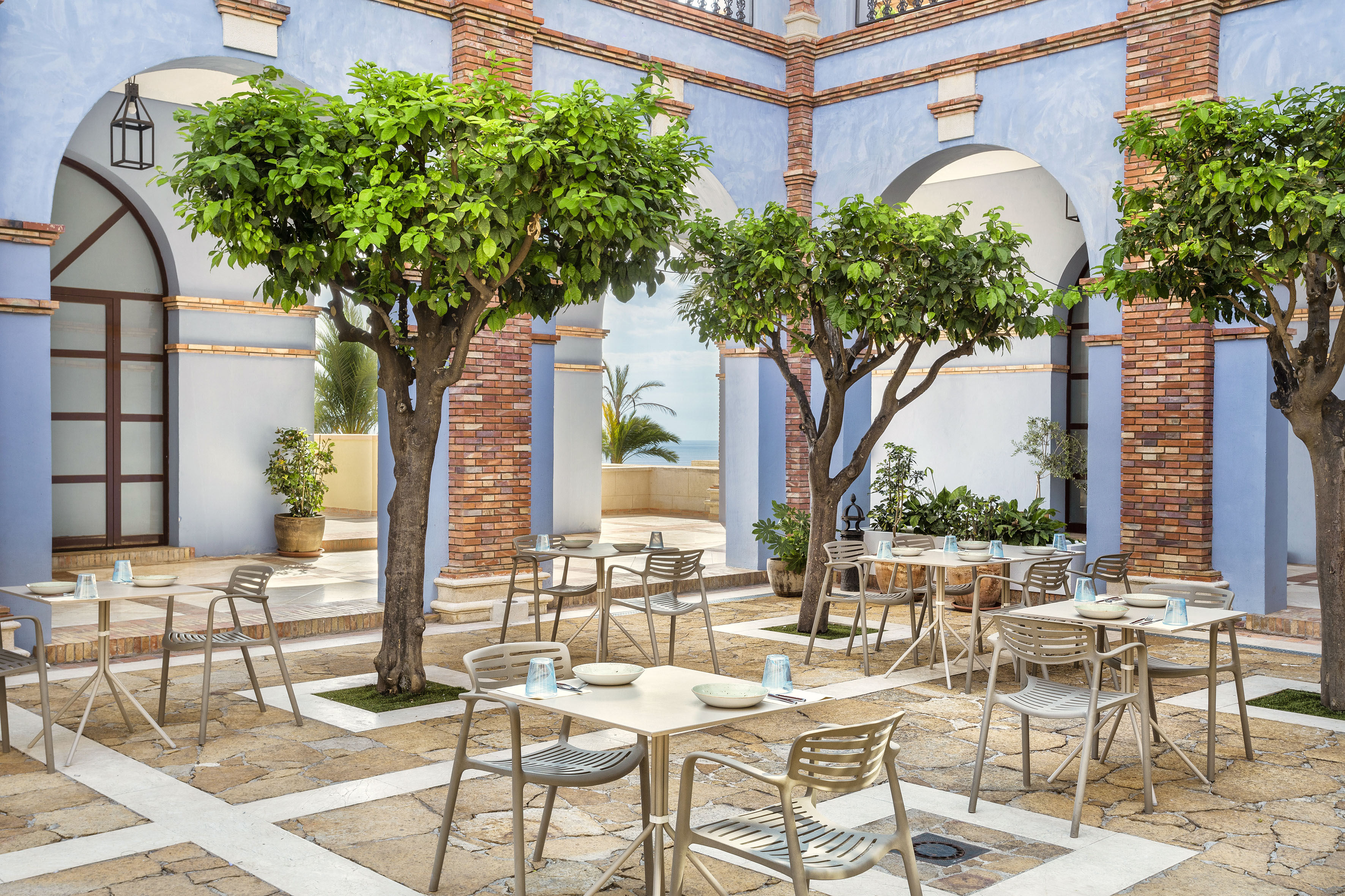 Mediterranean resort courtyard with al fresco dining and ocean views.