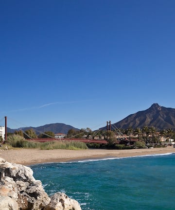 a beach with a bridge and a mountain in the background