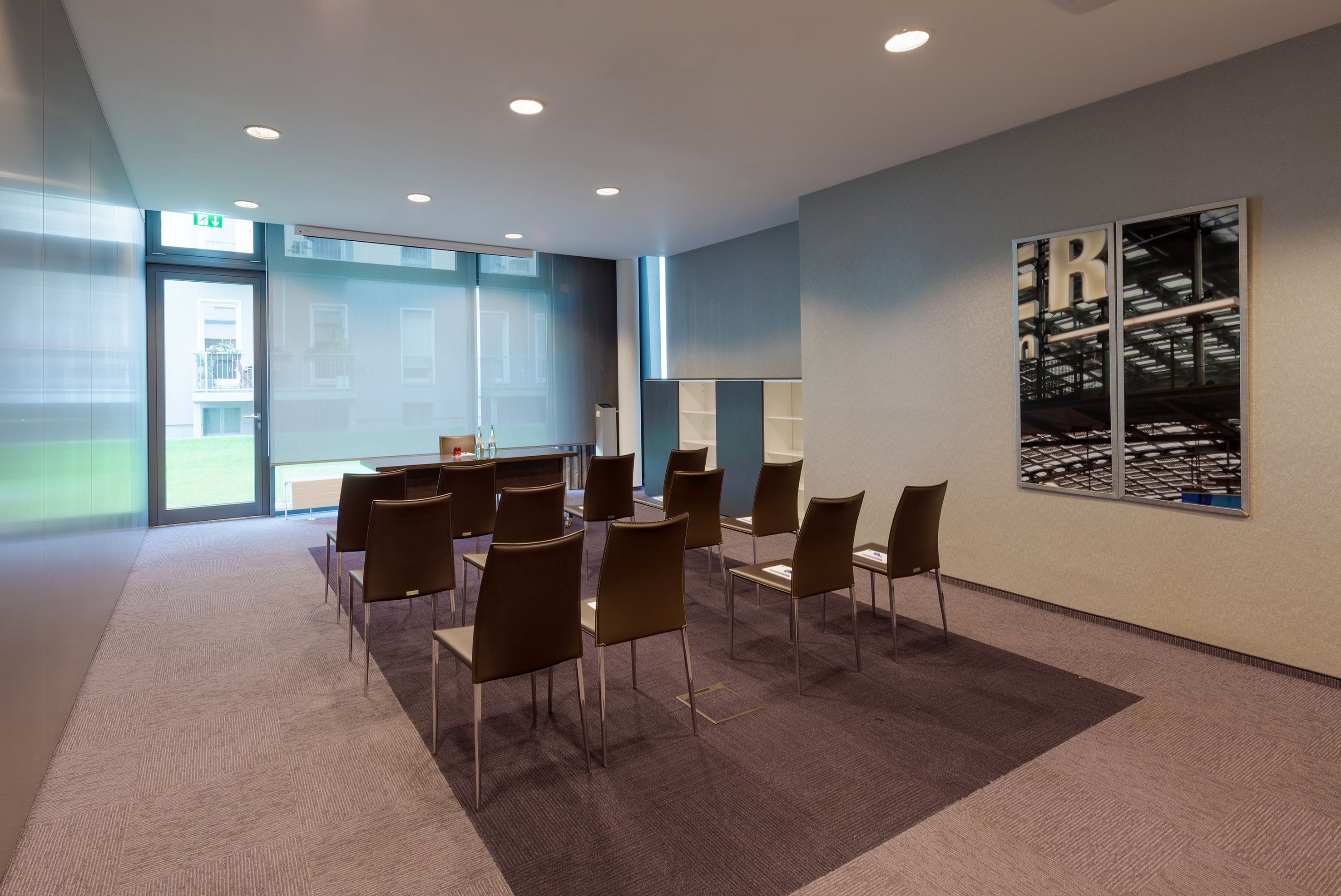 Modern conference room with brown chairs, long table, windows, and patterned carpet.