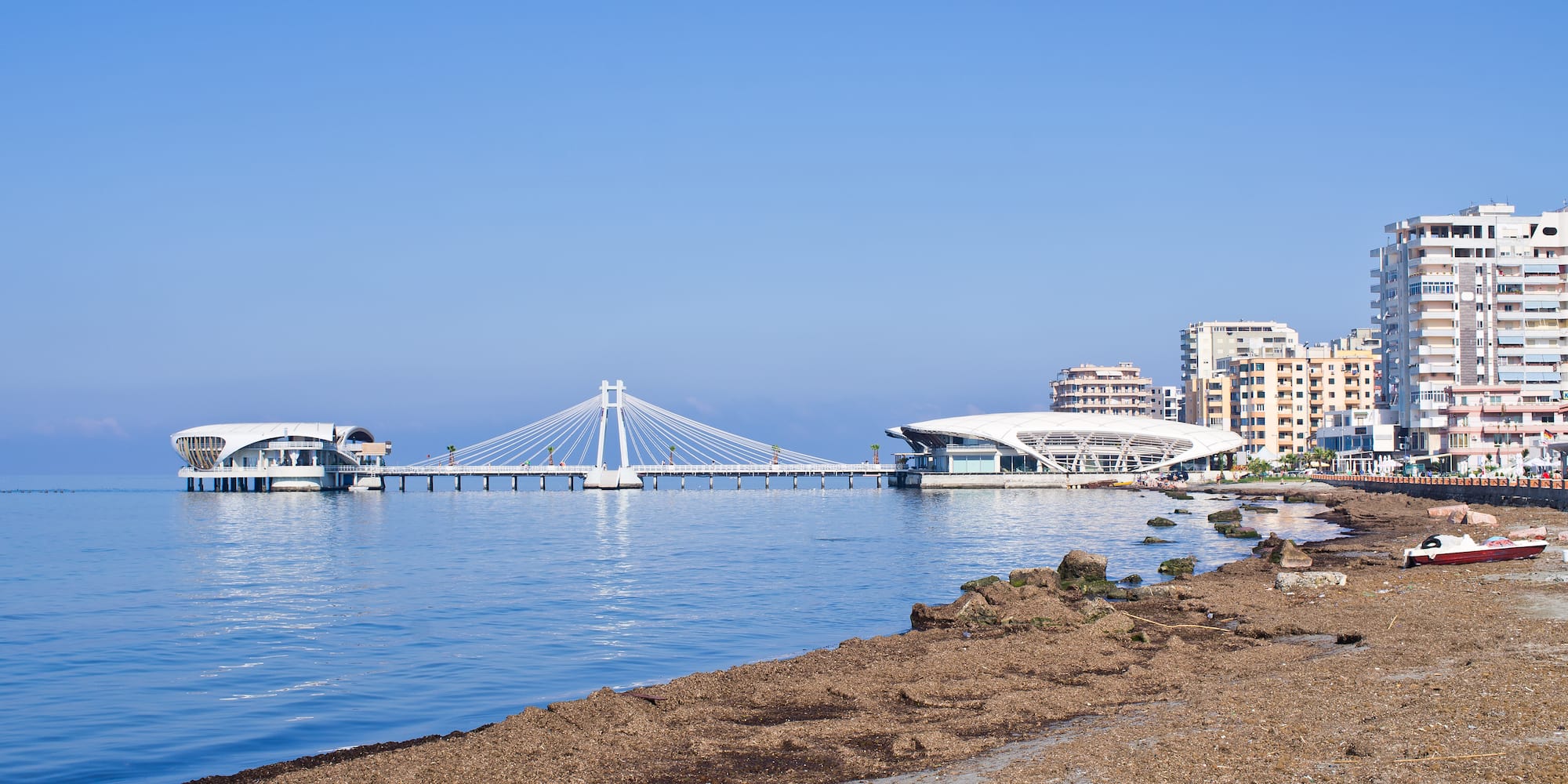 a beach with a bridge and buildings in the background