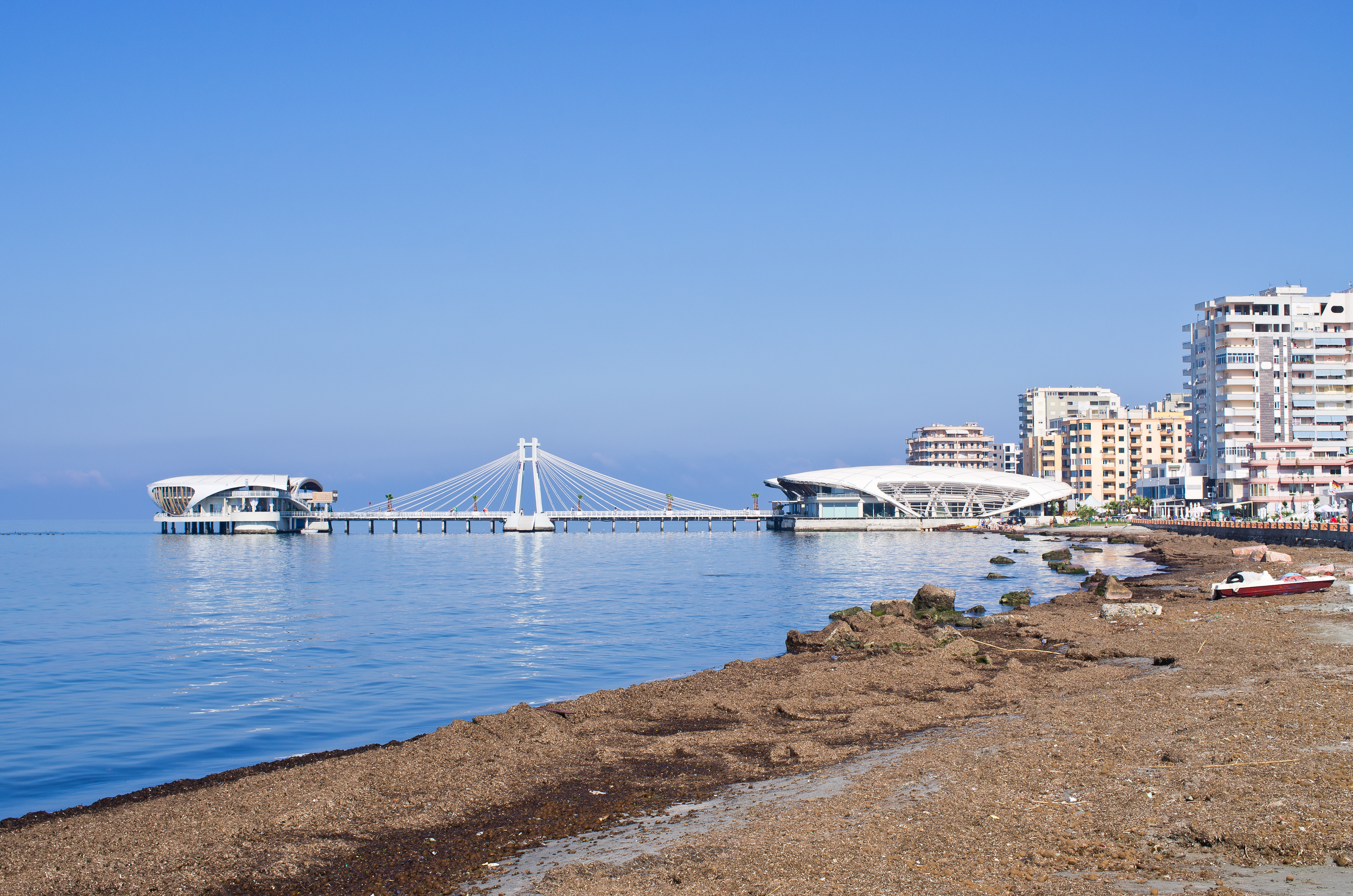 a beach with a bridge and buildings in the background