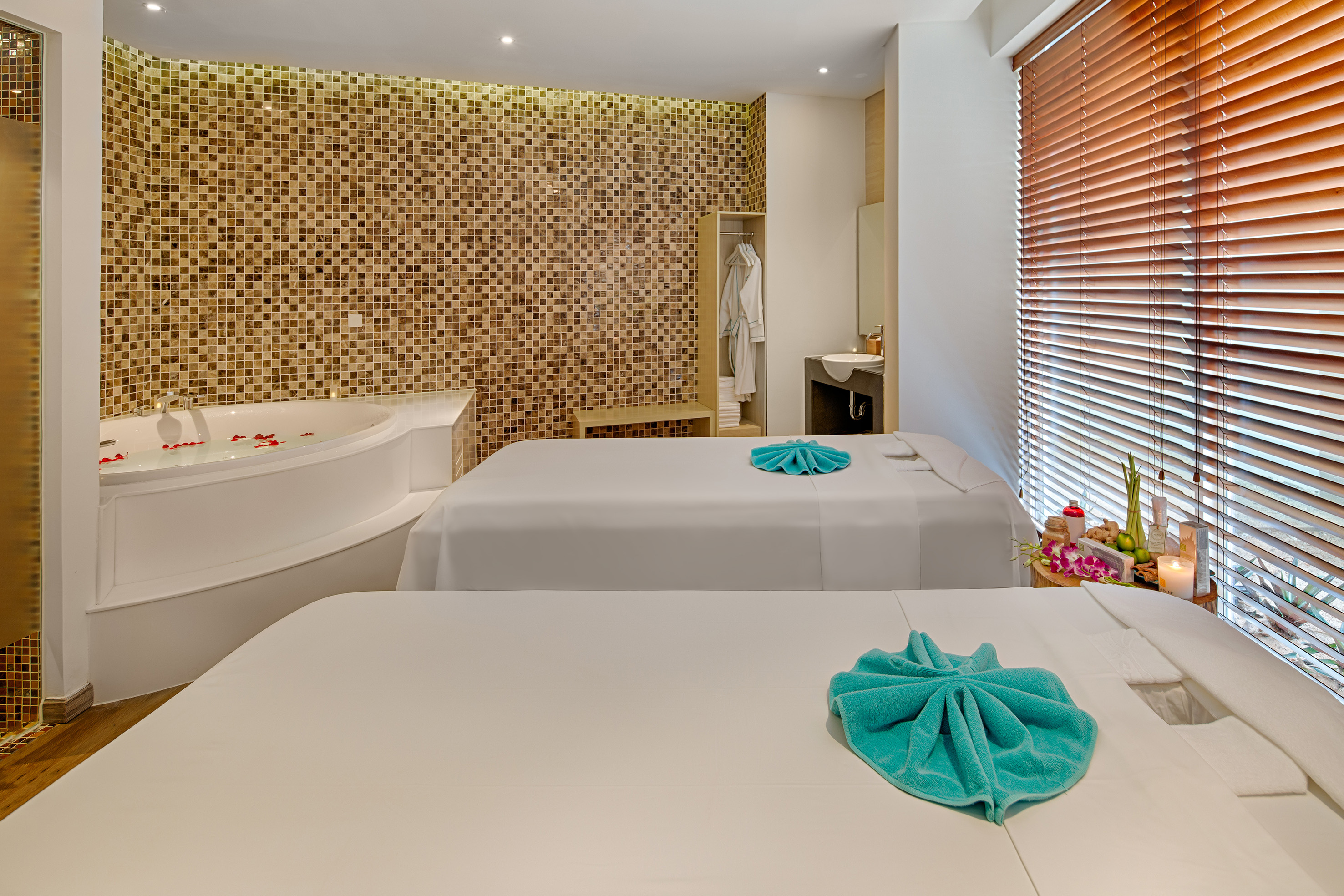 Luxurious spa with two massage tables, jacuzzi, mosaic walls, and relaxation decor.