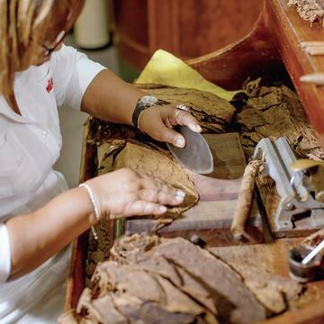 a woman rolling cigars with a grinder