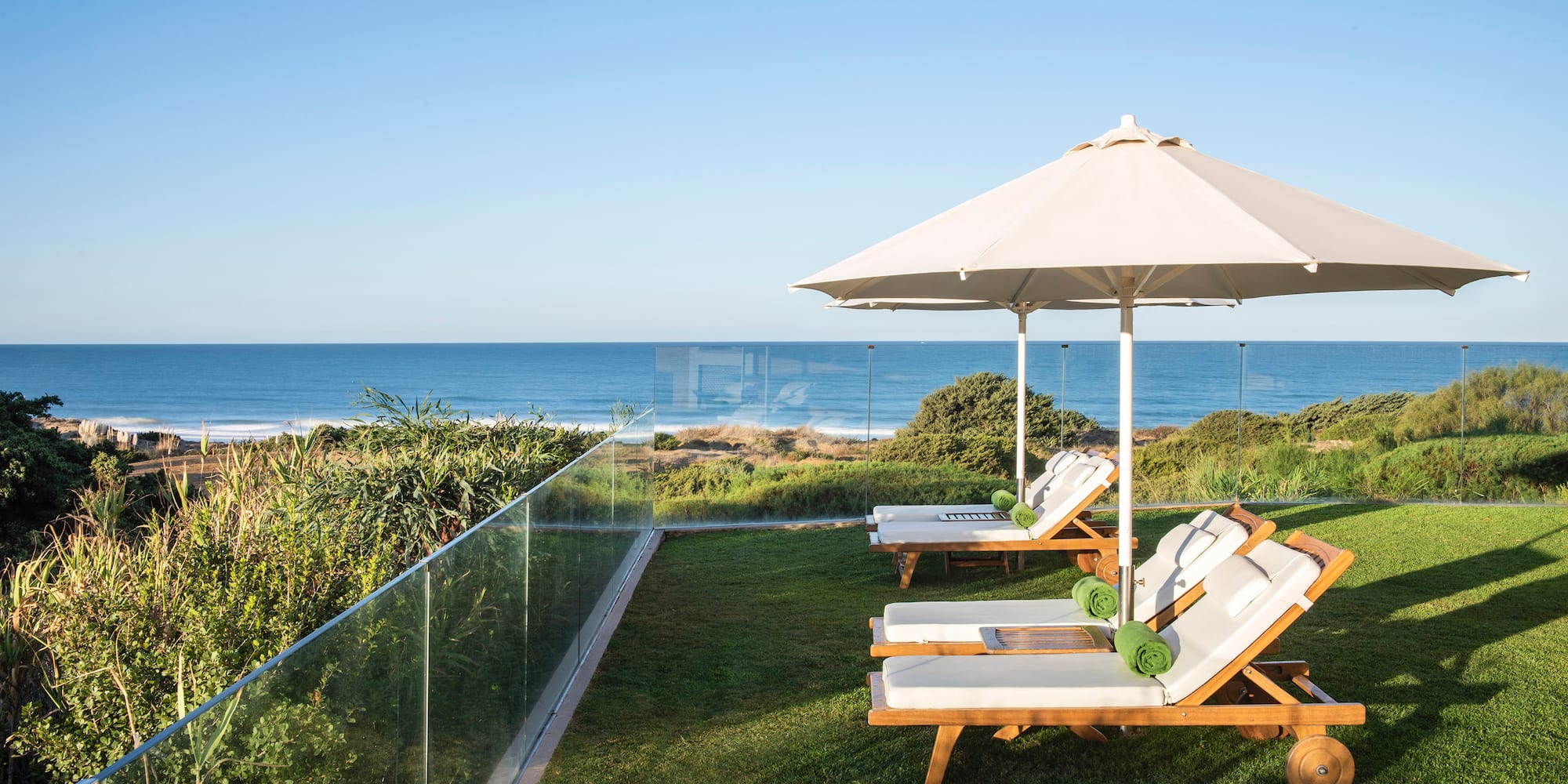 chairs and umbrellas on a lawn by the ocean