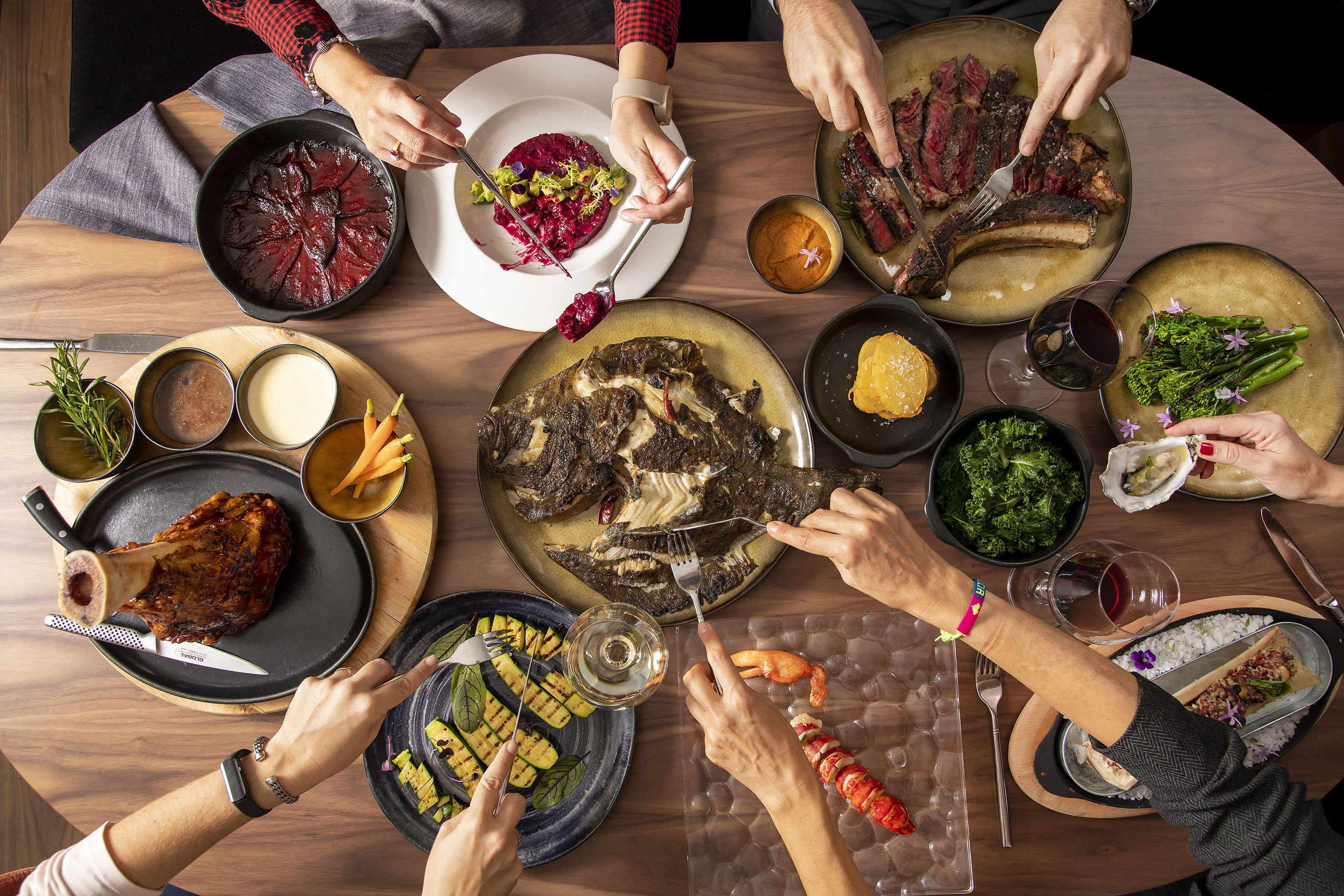 Gourmet dinner table with steak, whole fish, lobster, and diverse dishes.