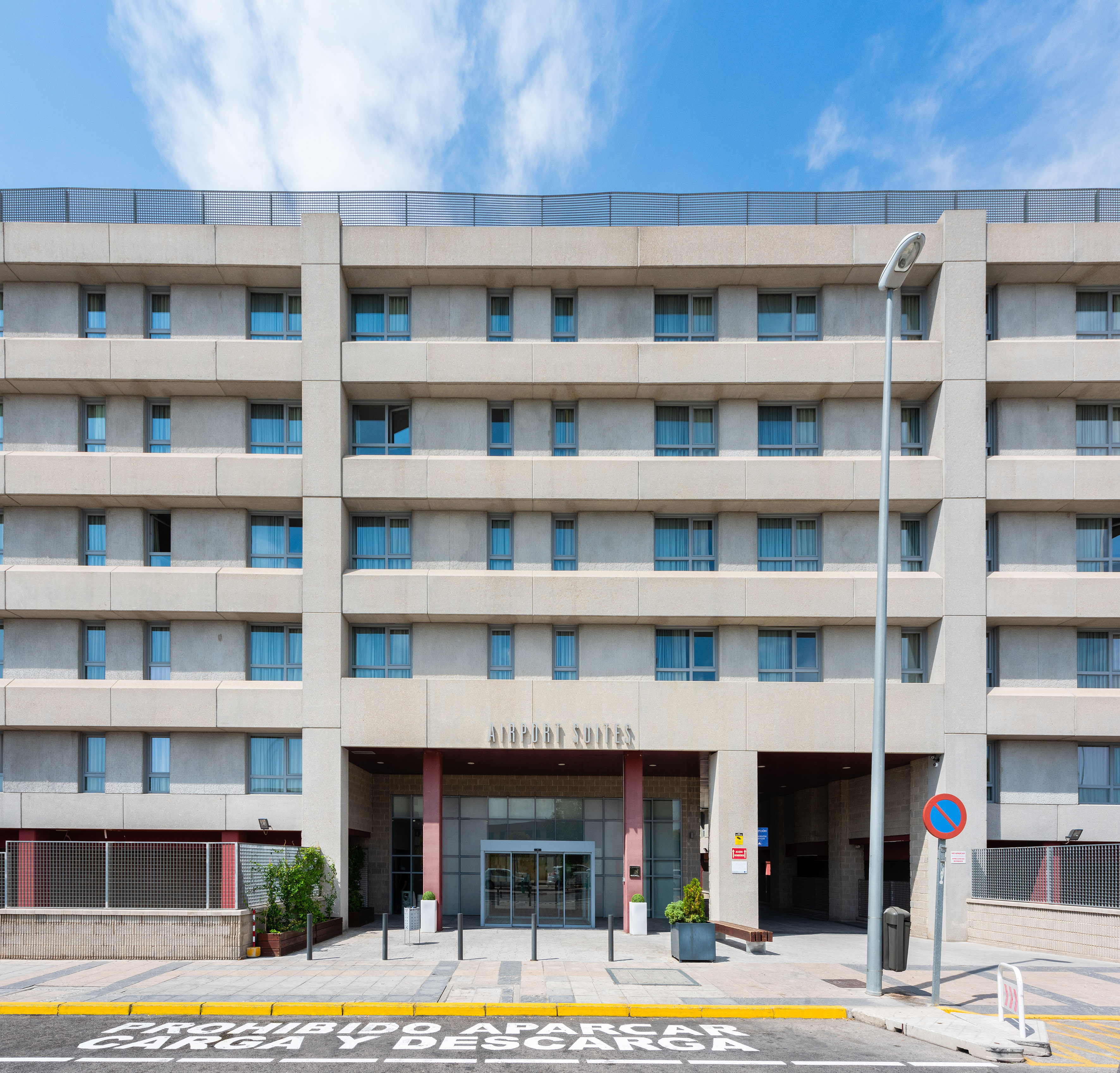 Airport Suites hotel facade, concrete structure with many windows.