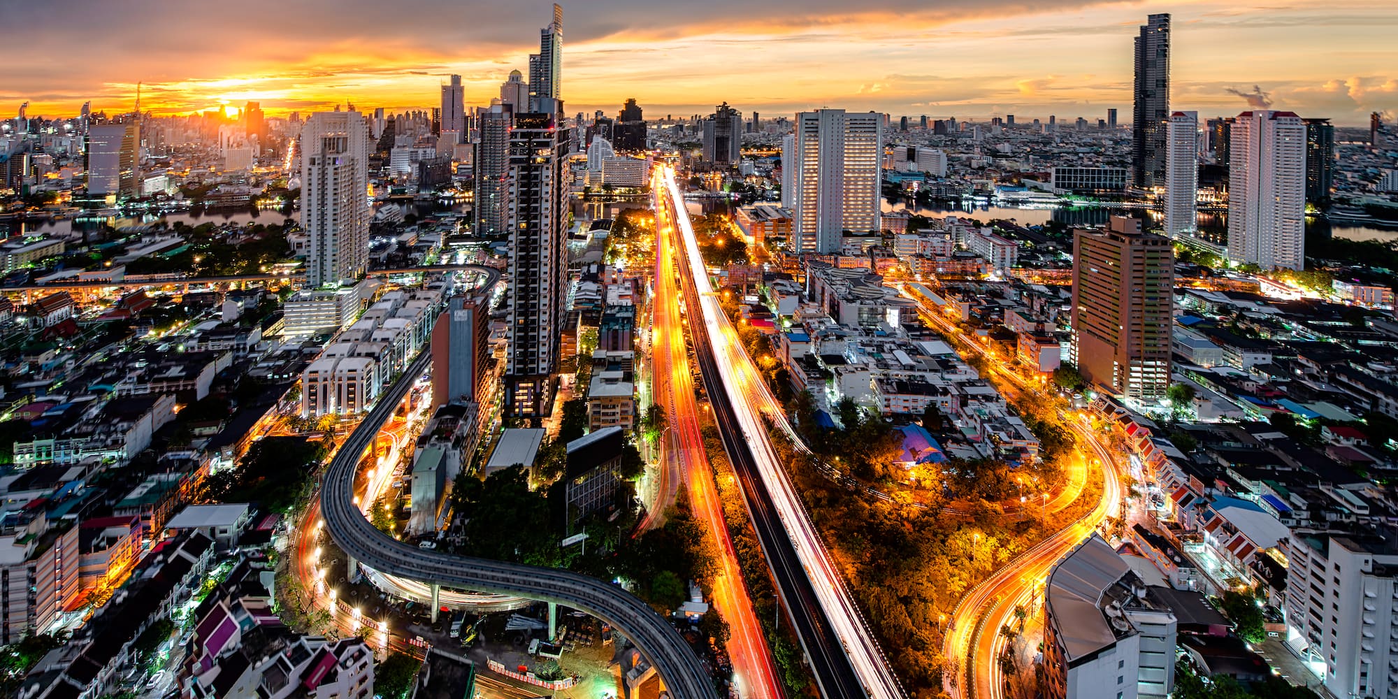 City skyline at sunset with bright traffic light trails and tall buildings.