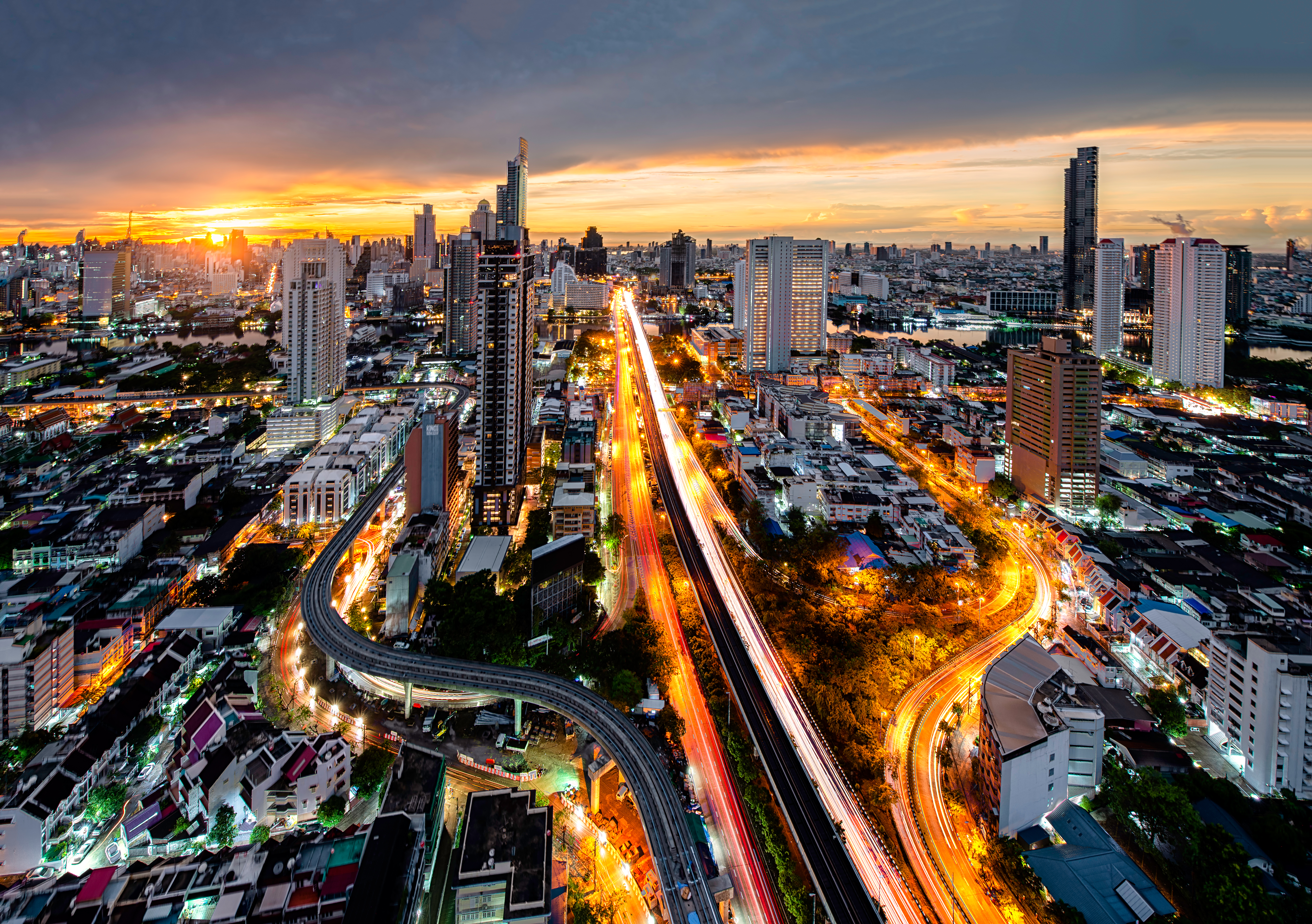City skyline at sunset with bright traffic light trails and tall buildings.