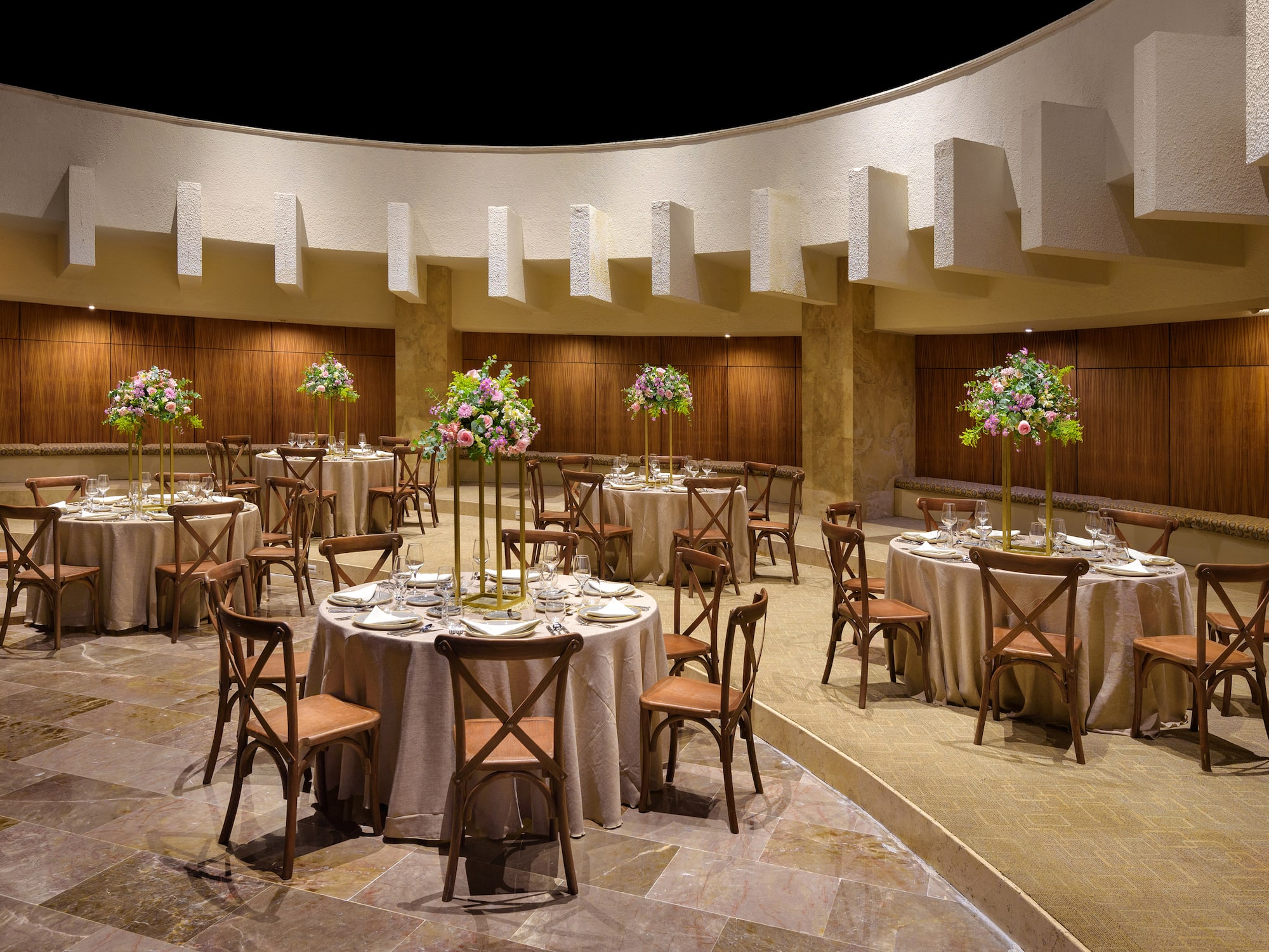 Modern event venue with set dining tables and elegant floral centerpieces.