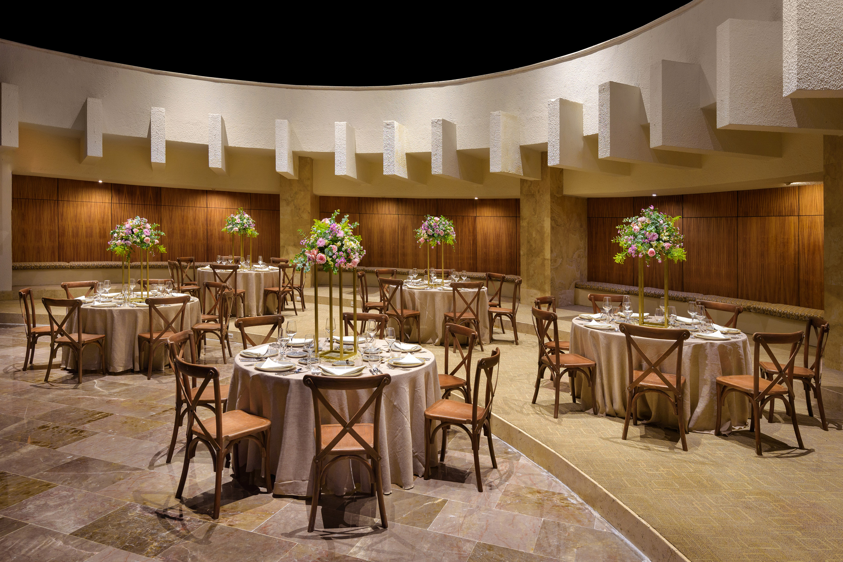 Modern event venue with set dining tables and elegant floral centerpieces.