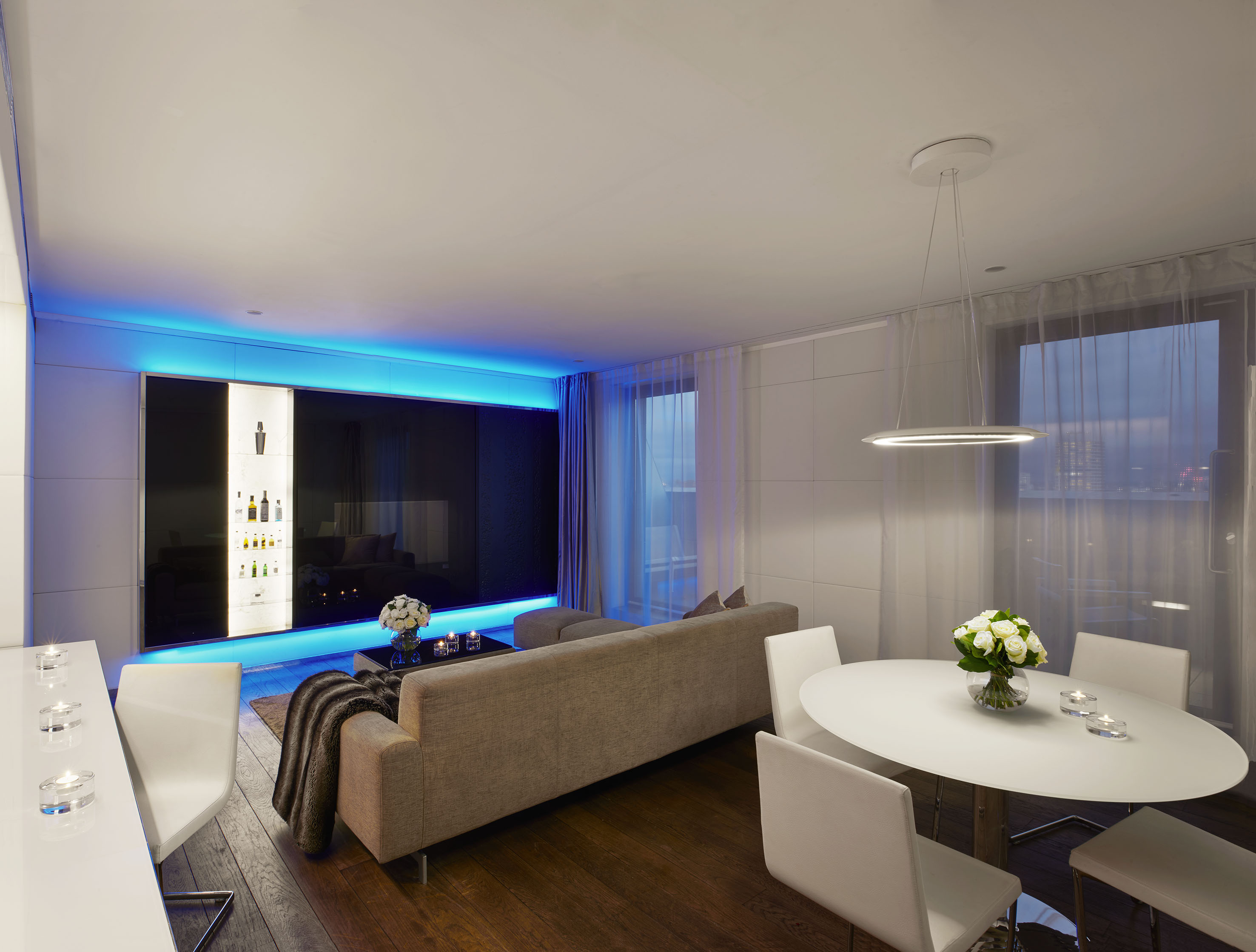 Sleek open-plan living and dining room with blue LED accent lighting and bar.