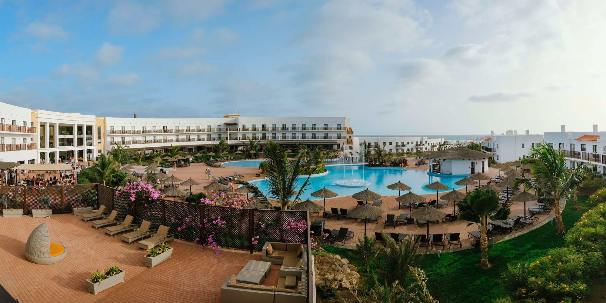 a pool with umbrellas and chairs in front of a building