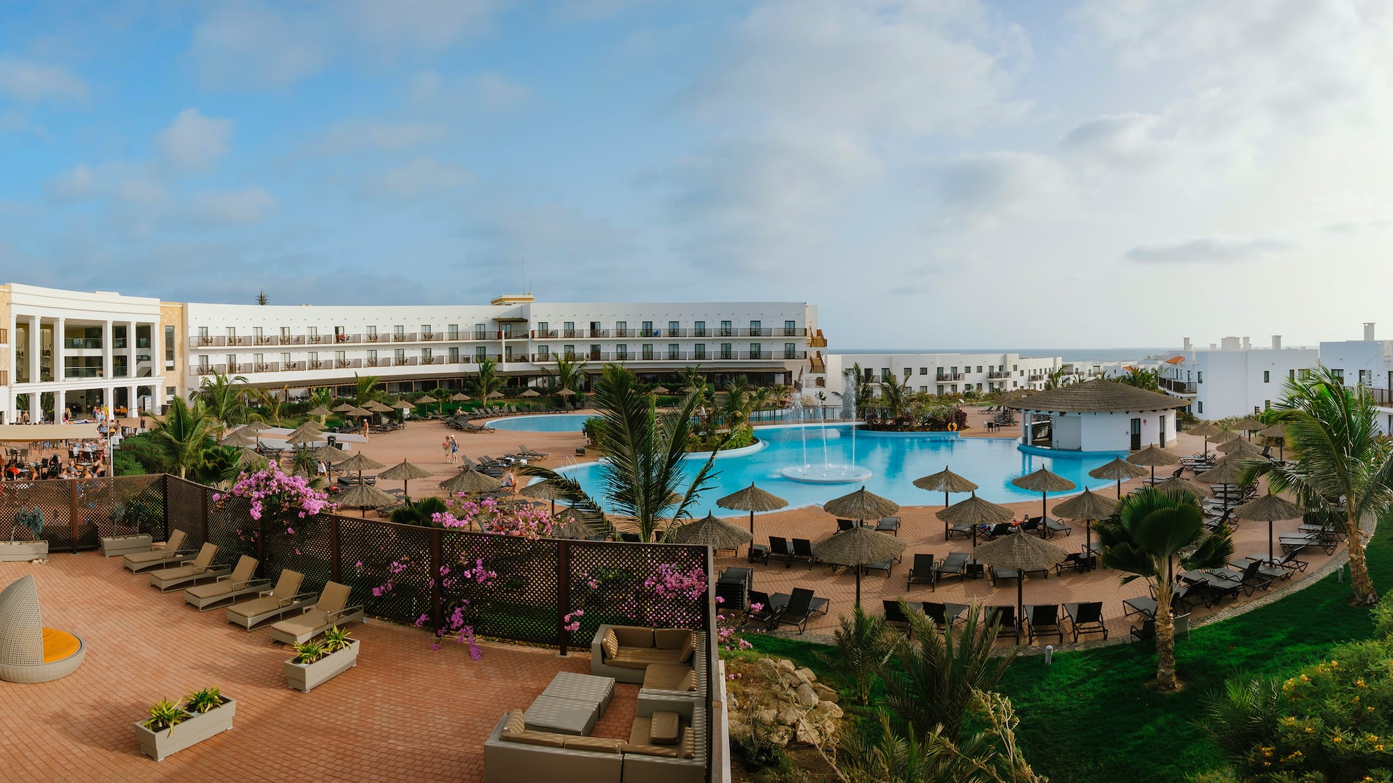 a pool with umbrellas and chairs in front of a building