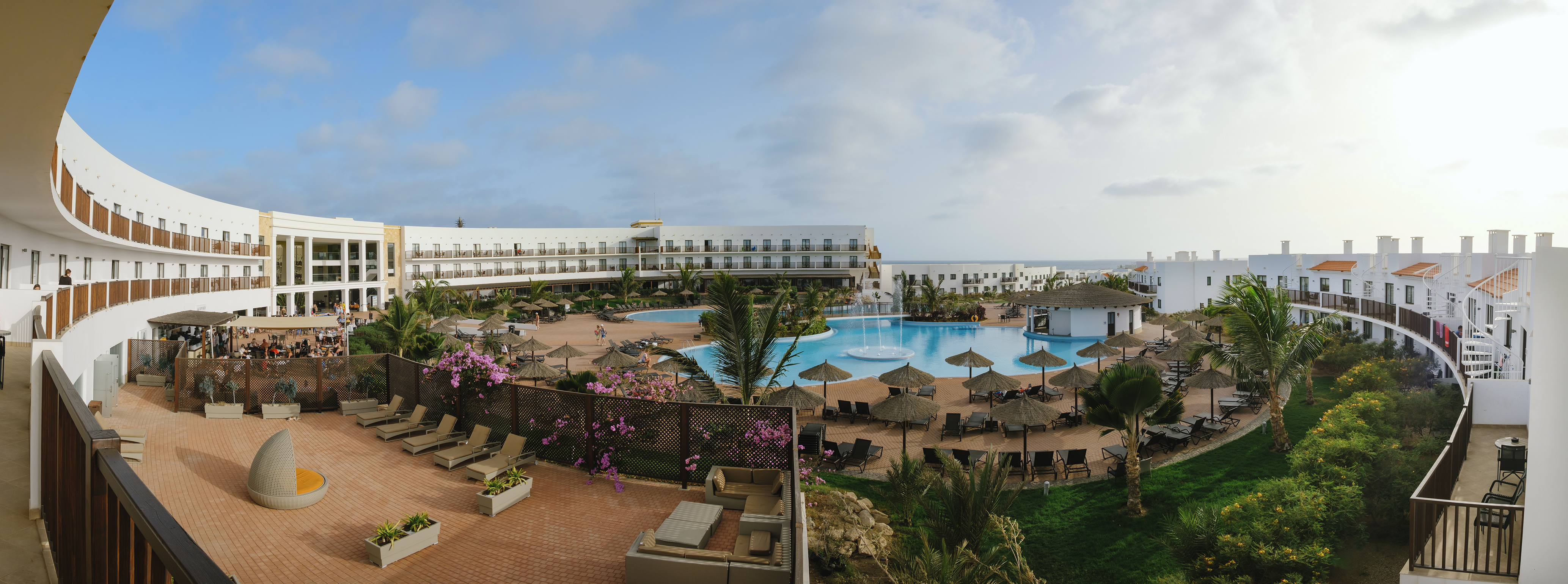a pool with umbrellas and chairs in front of a building