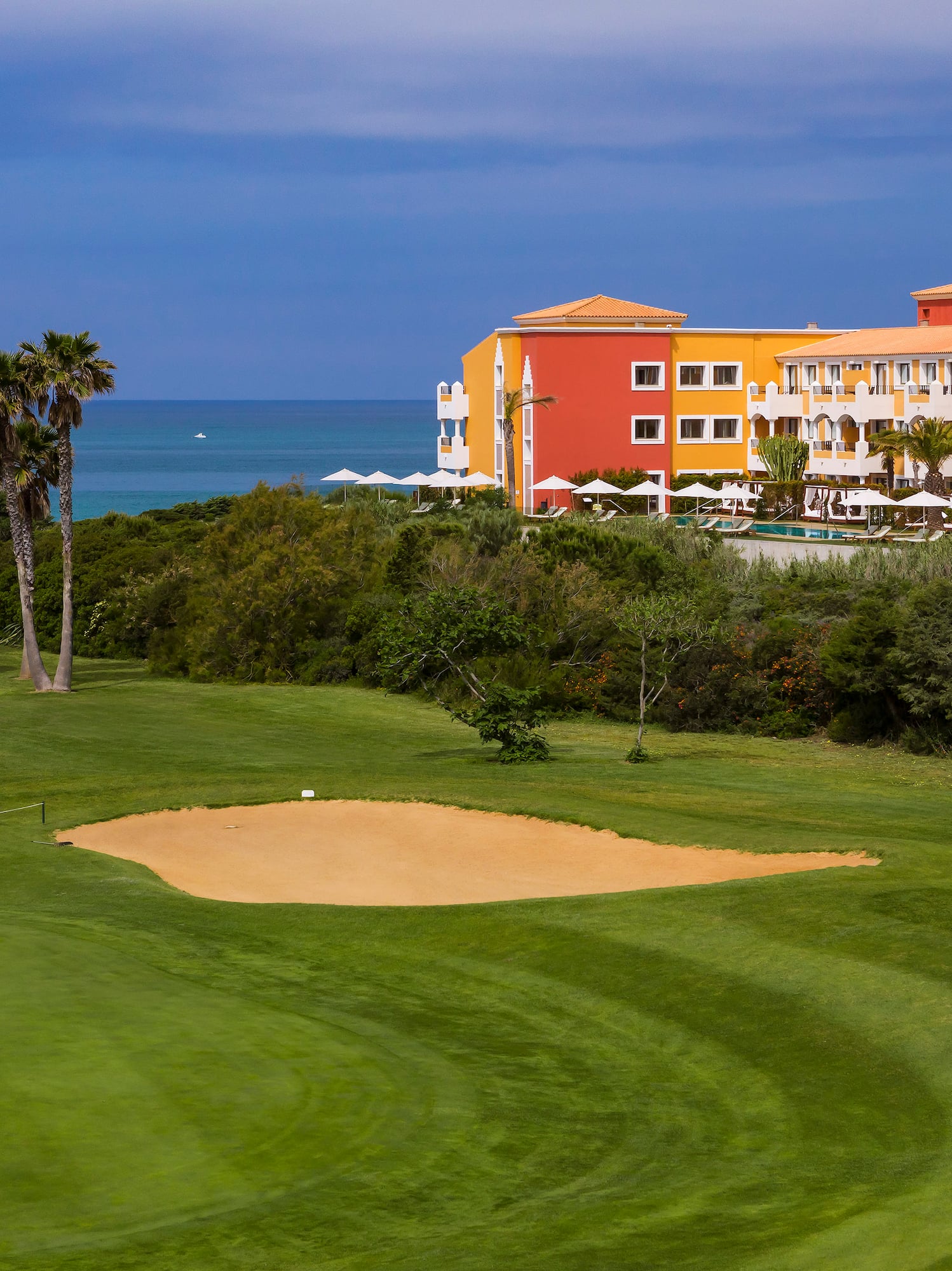 a golf course with a sand trap and palm trees