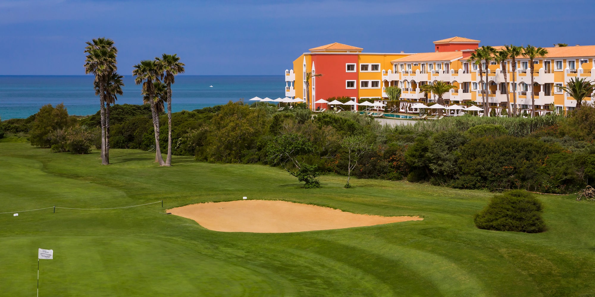 a golf course with a sand trap and palm trees