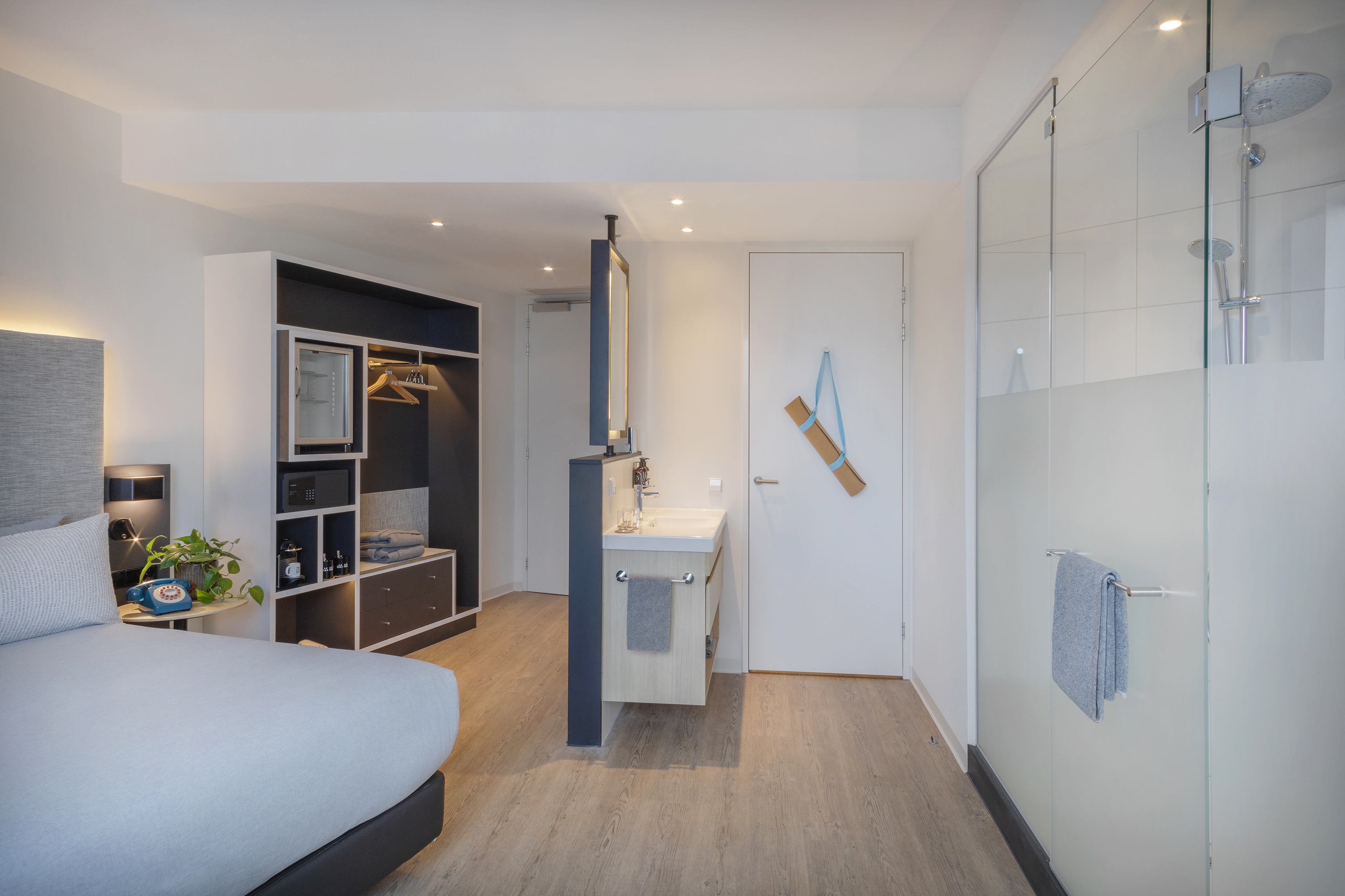 Stylish hotel room featuring bed, built-in wardrobe, vanity, and walk-in shower.