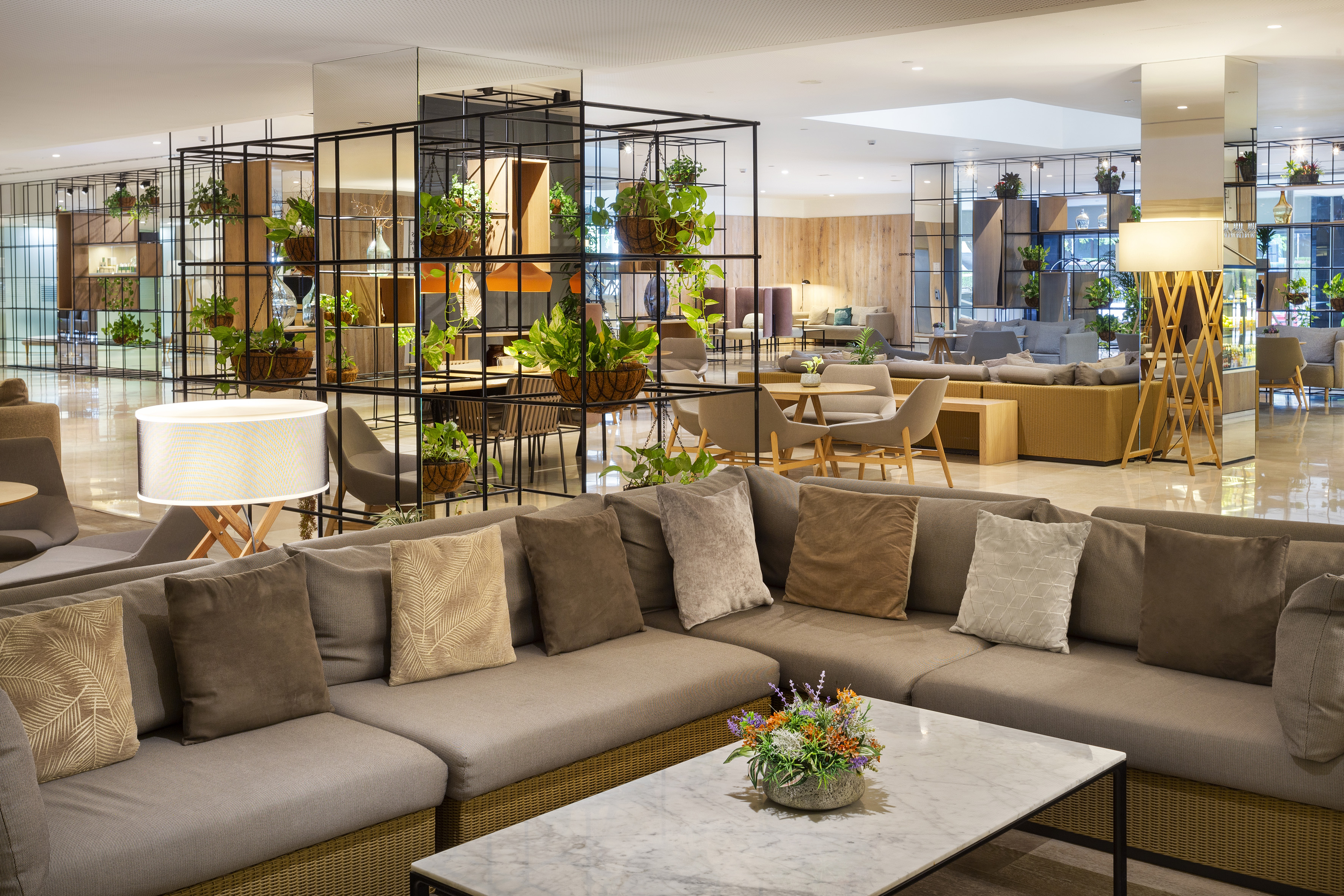 Hotel lounge with modern sofa, plant dividers, and marble coffee table.