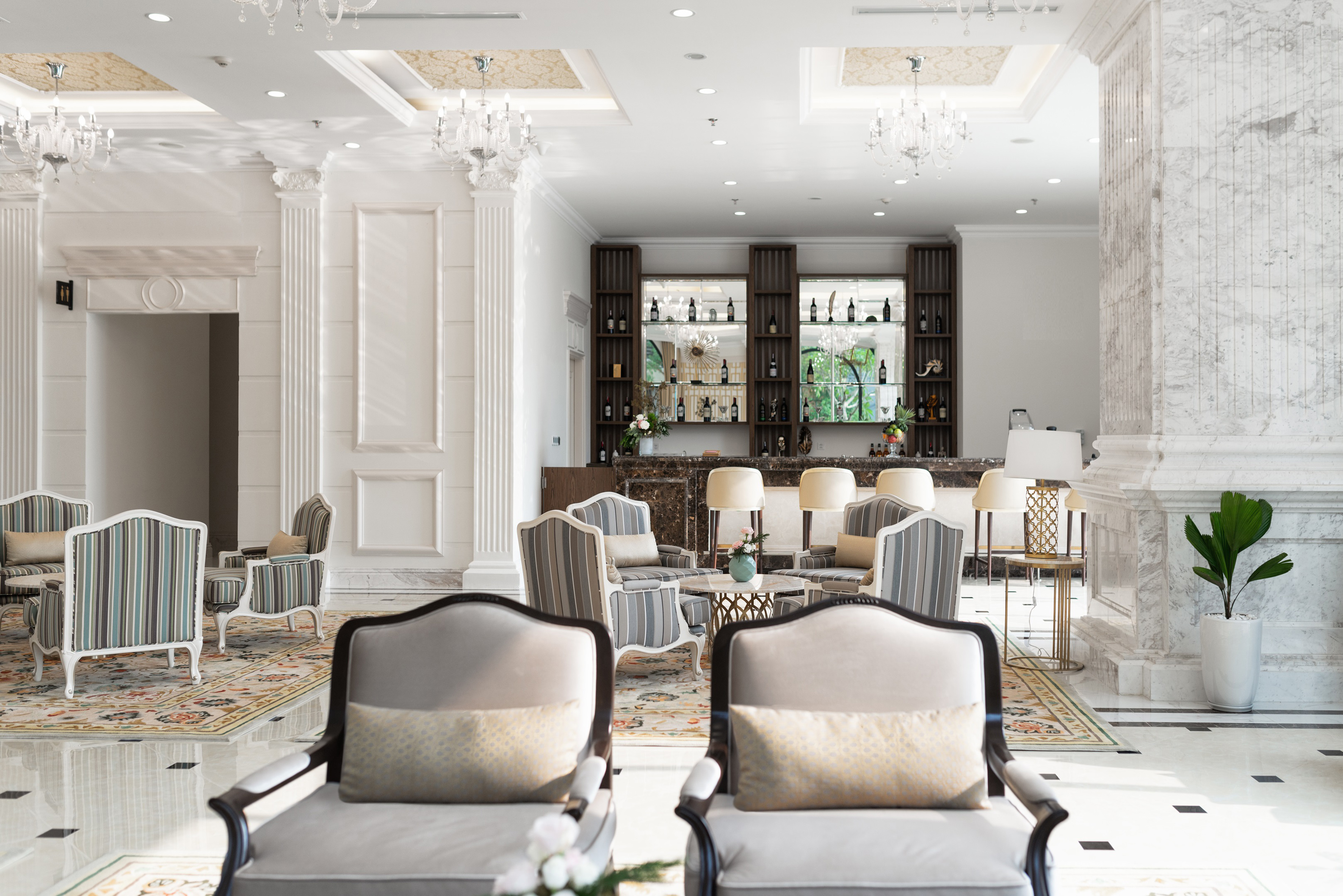 Luxury hotel lobby bar and lounge with chandeliers and comfortable seating.
